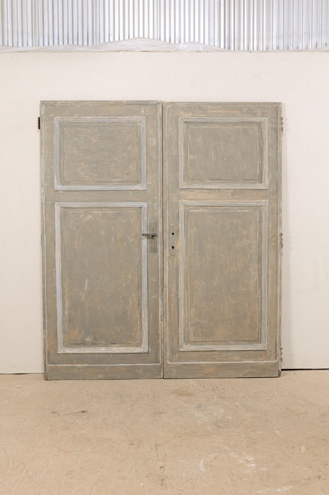 A pair of French painted wood doors from the 19th century. This pair of antique doors from France stand just shy of 7.5 feet in height, have recessed panels at front and backsides, with smaller square panel at top and rectangular panel within bottom