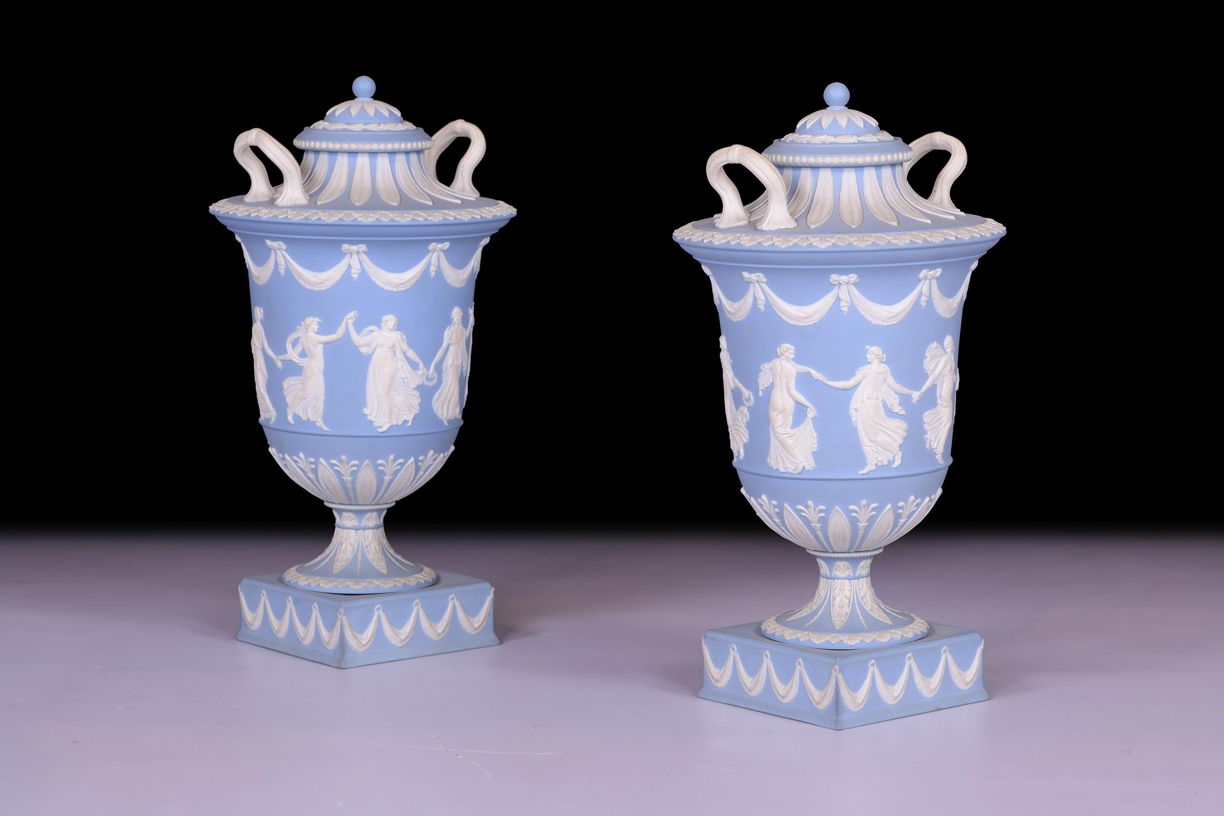 Most impressive pair of jasperware vases and covers from Wedgwood in the Neoclassical style. Composed of a baluster form, the shoulder is flanked by twin loop scroll handles, with spire finial radiating stiff-leaf tips covers the form. Neoclassical