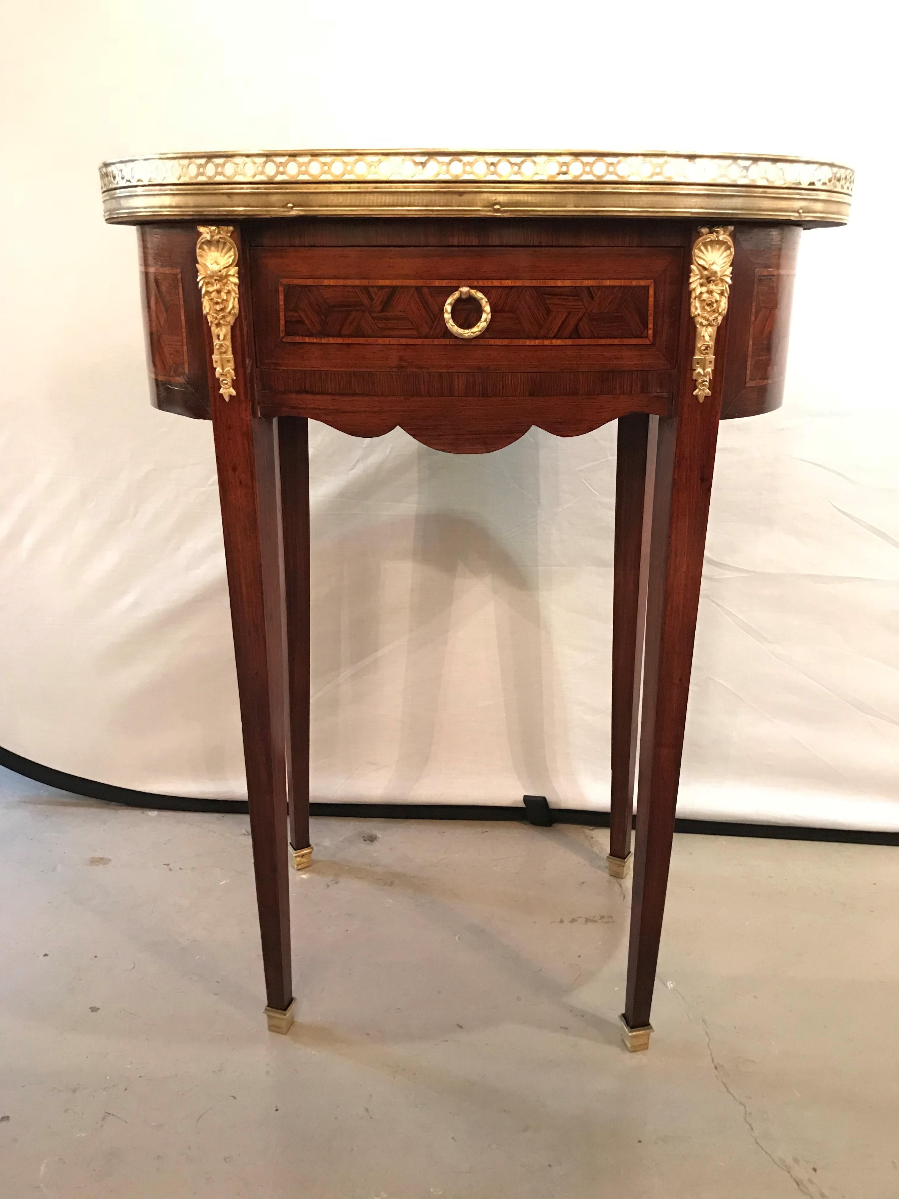 Pair of 19th century parquetry inlaid oval rose veined marble-top end tables or lamp tables. Each having a marble top set in a galleried bronze frame supported by a case of one center drawer with bronze flanked sides and fine inlays. The whole with