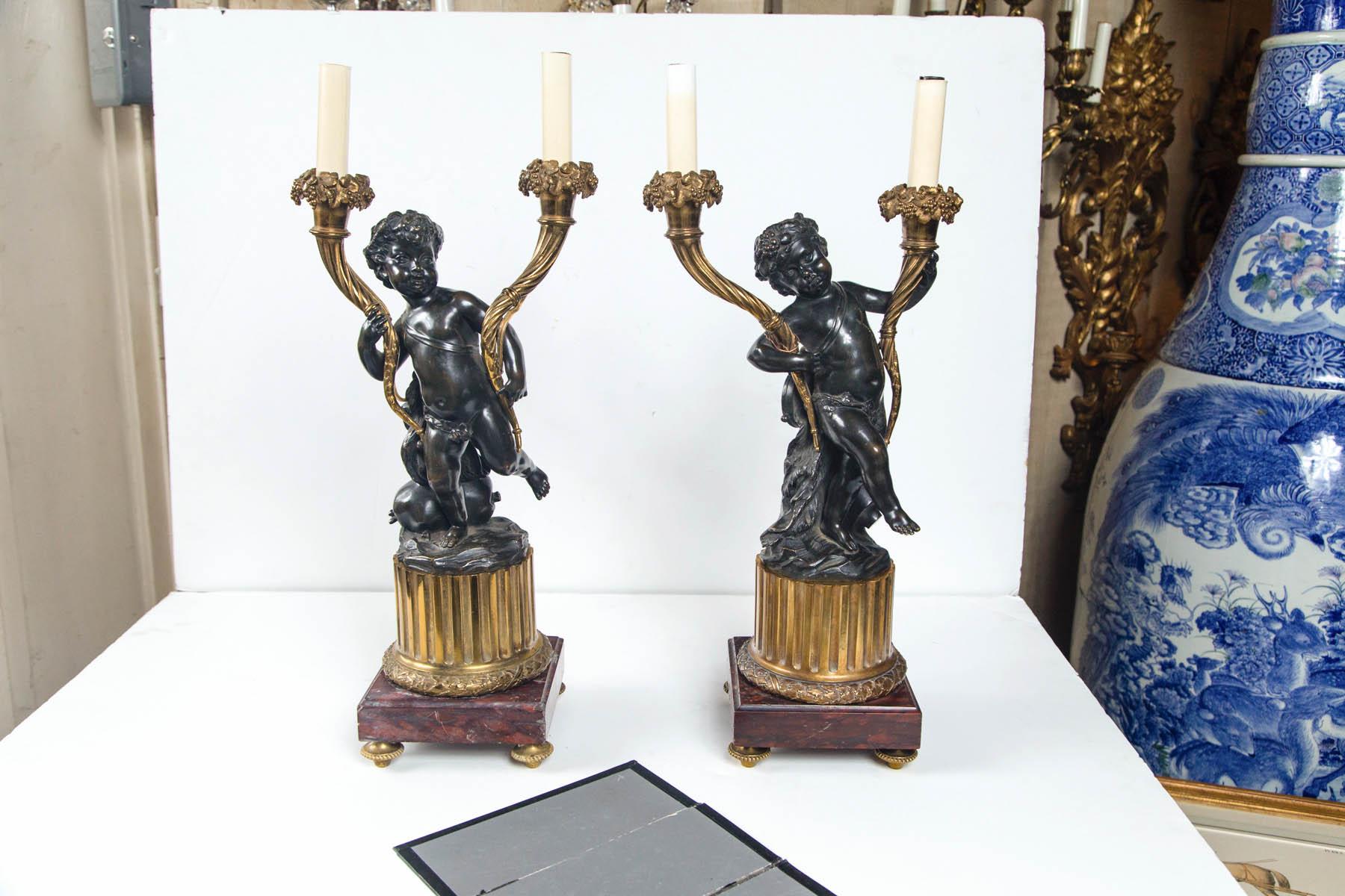 The figures representing air and water. Each holding a candelabra arm in each hand. The candelabra arms of gold lacquered bronze.
Raise on a round gold lacquered bronze short fluted column above a wreath. The base of rouge Royale marble with gold