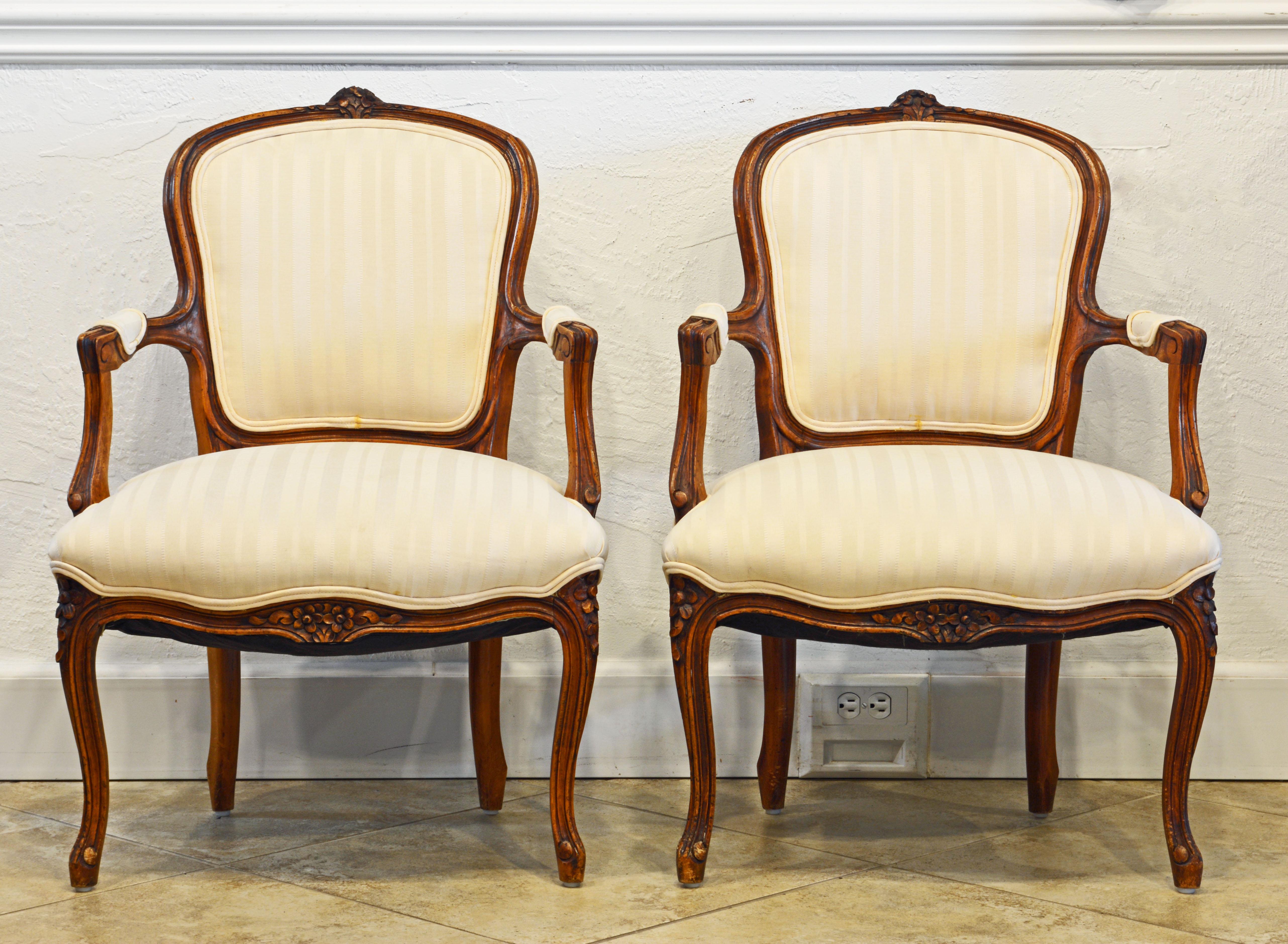 This pair of French Louis XV style carved armchairs are especially charming due to their relatively small size. They feature well carved walnut frames supporting upholstered backs, seats and armrests.