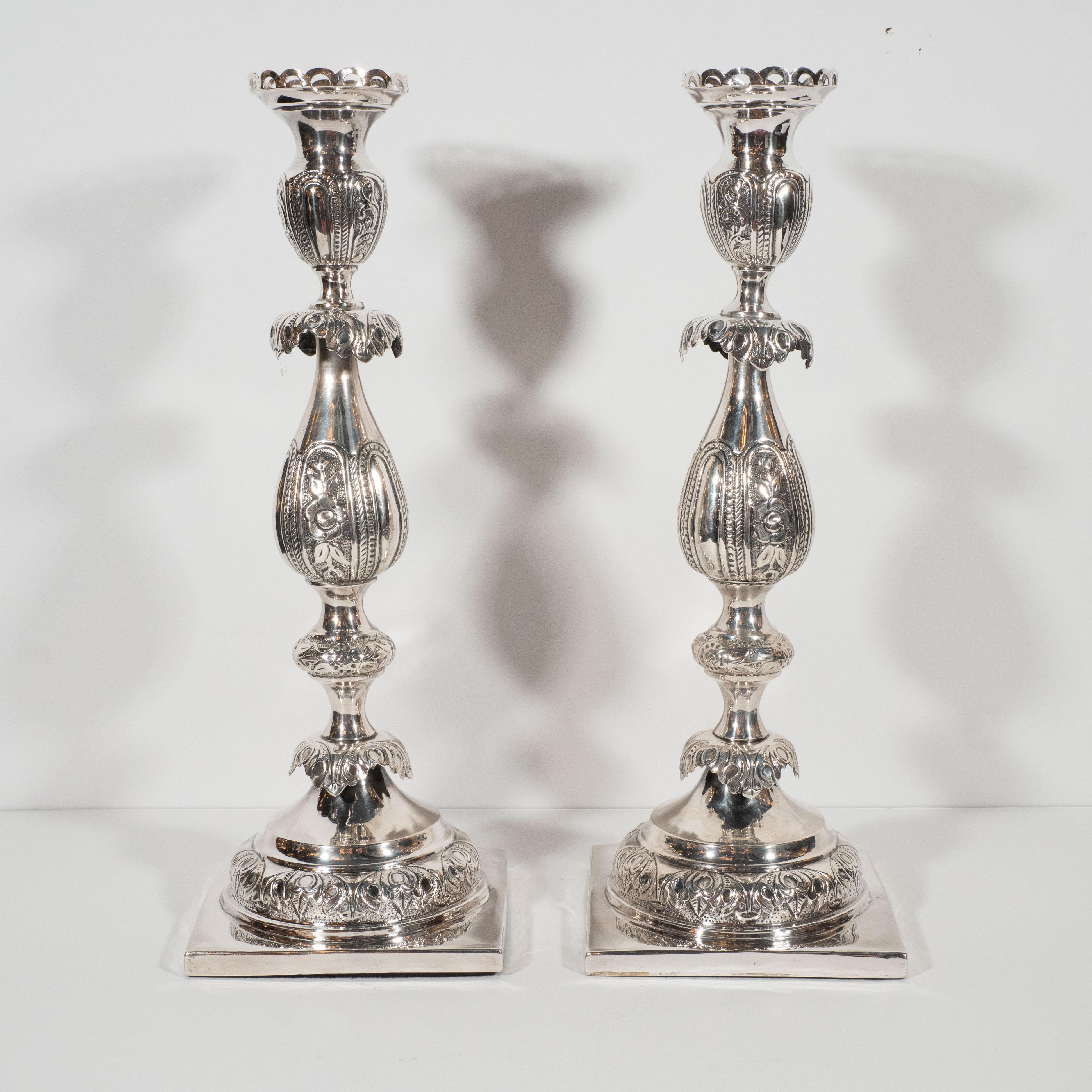 This elegant pair of neoclassical sterling silver Sabbath candlesticks were realized in Poland at the end of the 19th century. Rising from a square base, each candlestick offers an undulating balustrade form with a wealth of hand inscribed repoussé