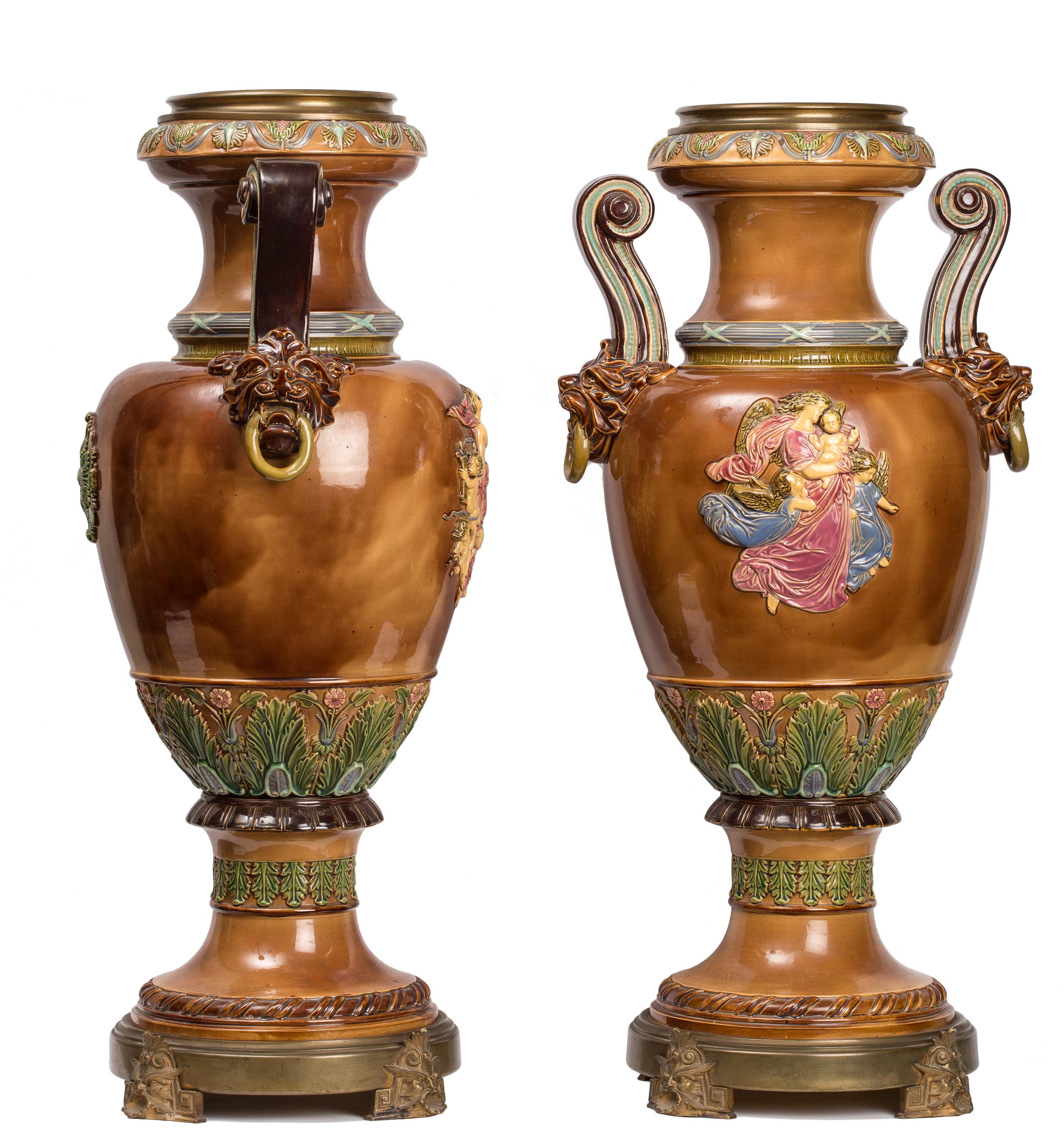 A matched pair of late 19th century Bohemian / German majolica porcelain urns. With a contrasting mix of Christian, mythological, grotesque and neoclassical elements, they exemplify the highly decorative, 