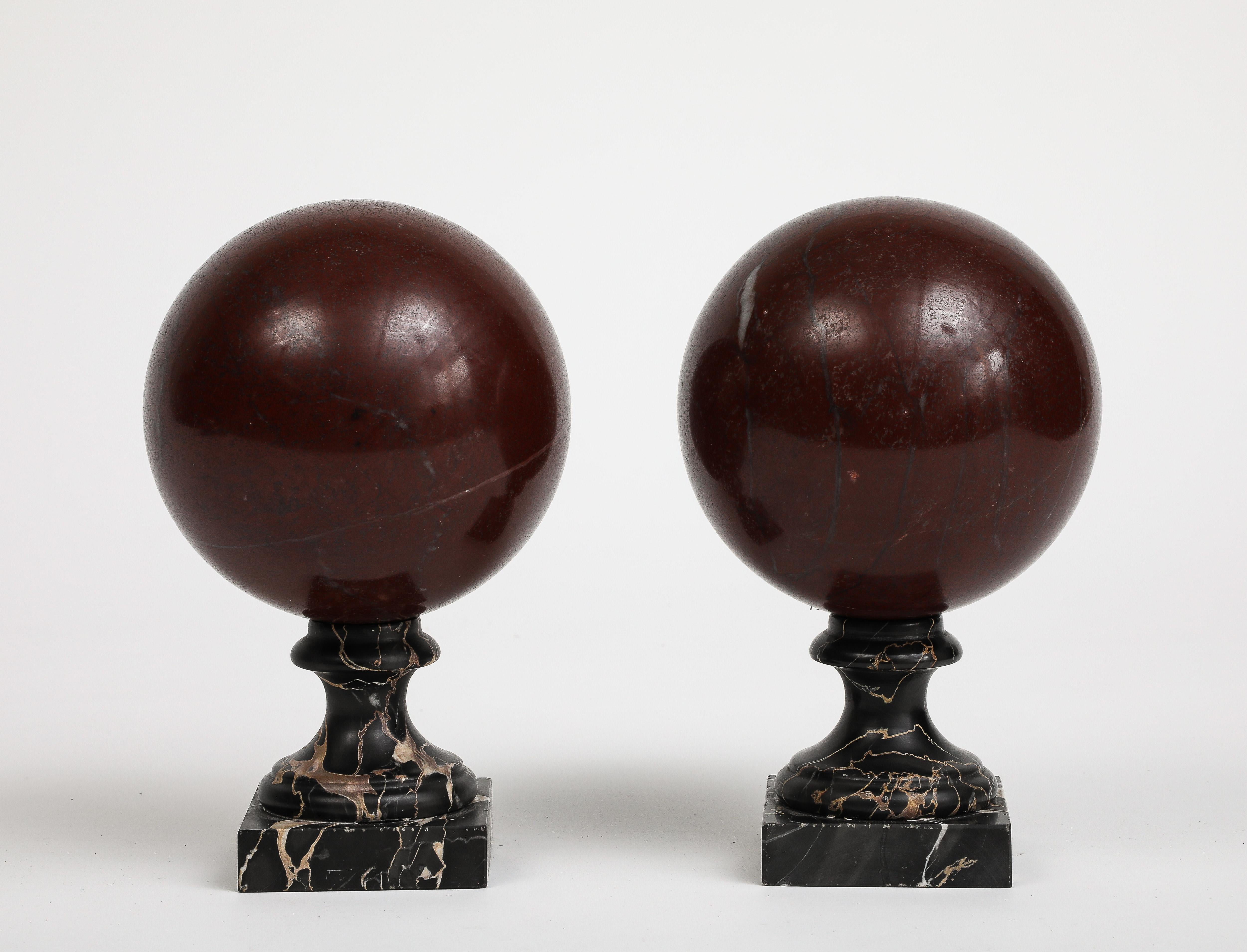 Pair of 19th century red marble spheres on black marble stands; the spheres are not attached to the bases. 
Base alone is 3.25