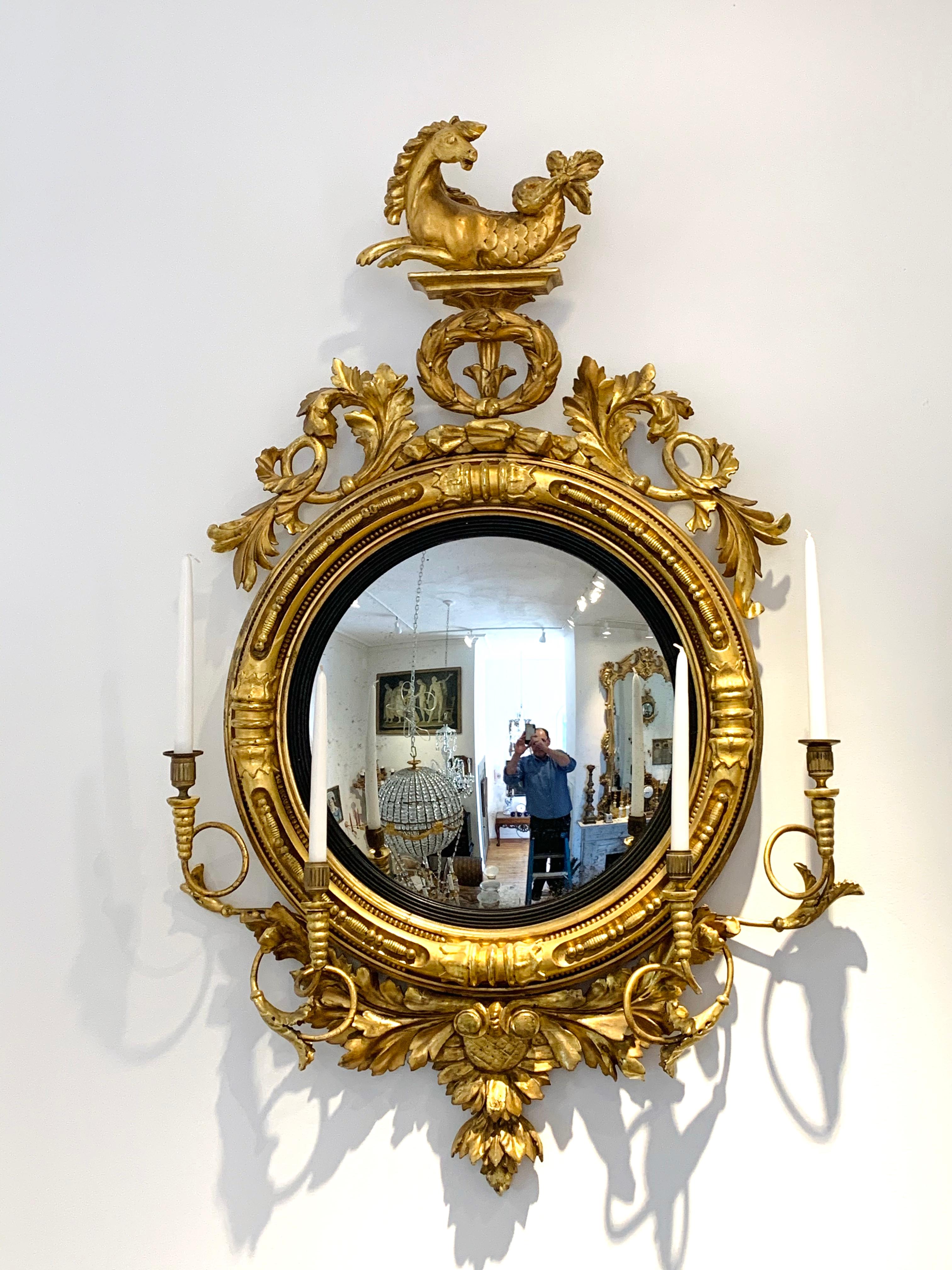 Rare pair of Regency convex or bullseye mirrors --Original gilding being conserved and restored at the moment. Original girandole candle arms. Original convex mirrors and silvering --sunflower motif on bottom and true pair of Hippogryphs on top.