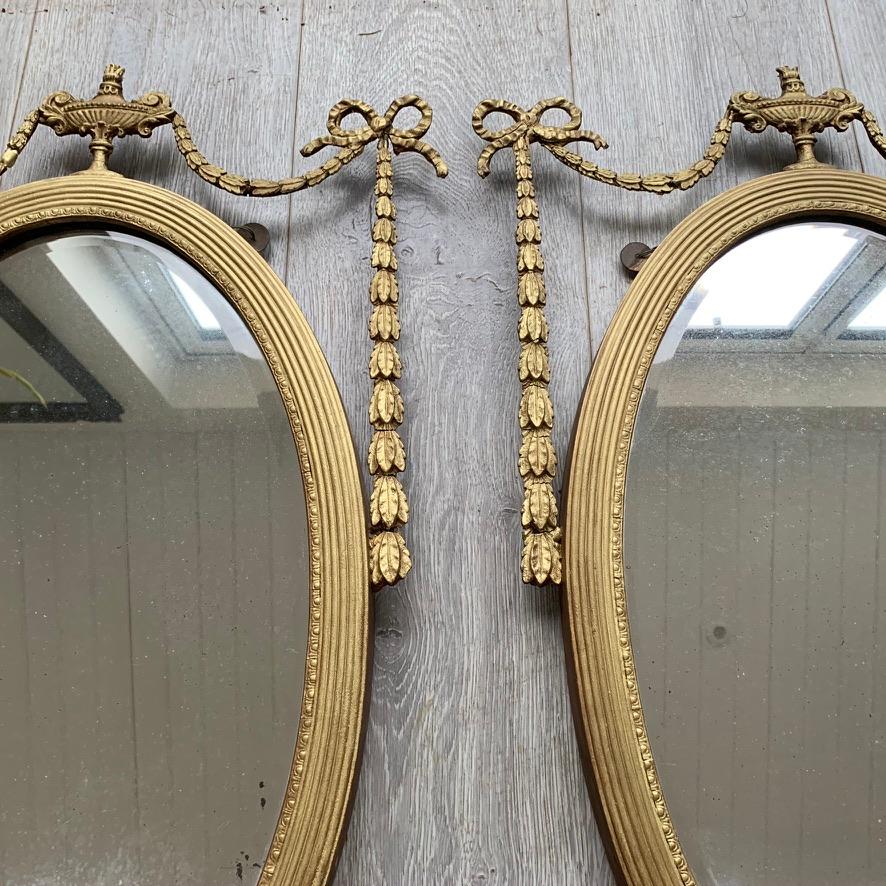 Very pretty pair of early 19th century English Regency oval gilt mirrors with urns, garlands and ribbons.
Good decorative pair of mirrors and a lovely size.
There are some losses to the ribbon plaster moulding at the bottom of one mirror and also