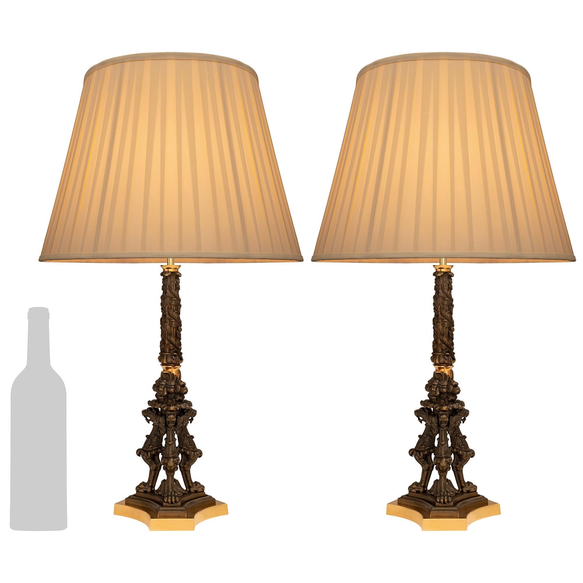 Une paire de lampes en bronze patiné et bronze doré de style Renaissance du XIXe siècle. Chaque lampe merveilleusement détaillée repose sur une base triangulaire aux bords marbrés et aux côtés inversés, et est soutenue par une plaque en bronze doré