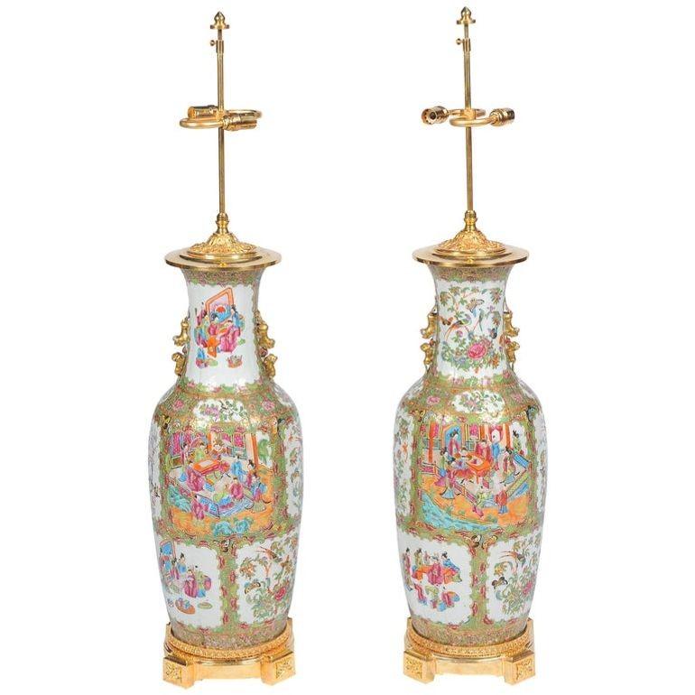 An impressive pair of 19th Century Chinese cantonese, rose medallion vases or lamps. Having panels of classical oriental scenes, also flowers, birds and butterflies amongst a green background of foliage. Gilded lion handles and mounted on ormolu