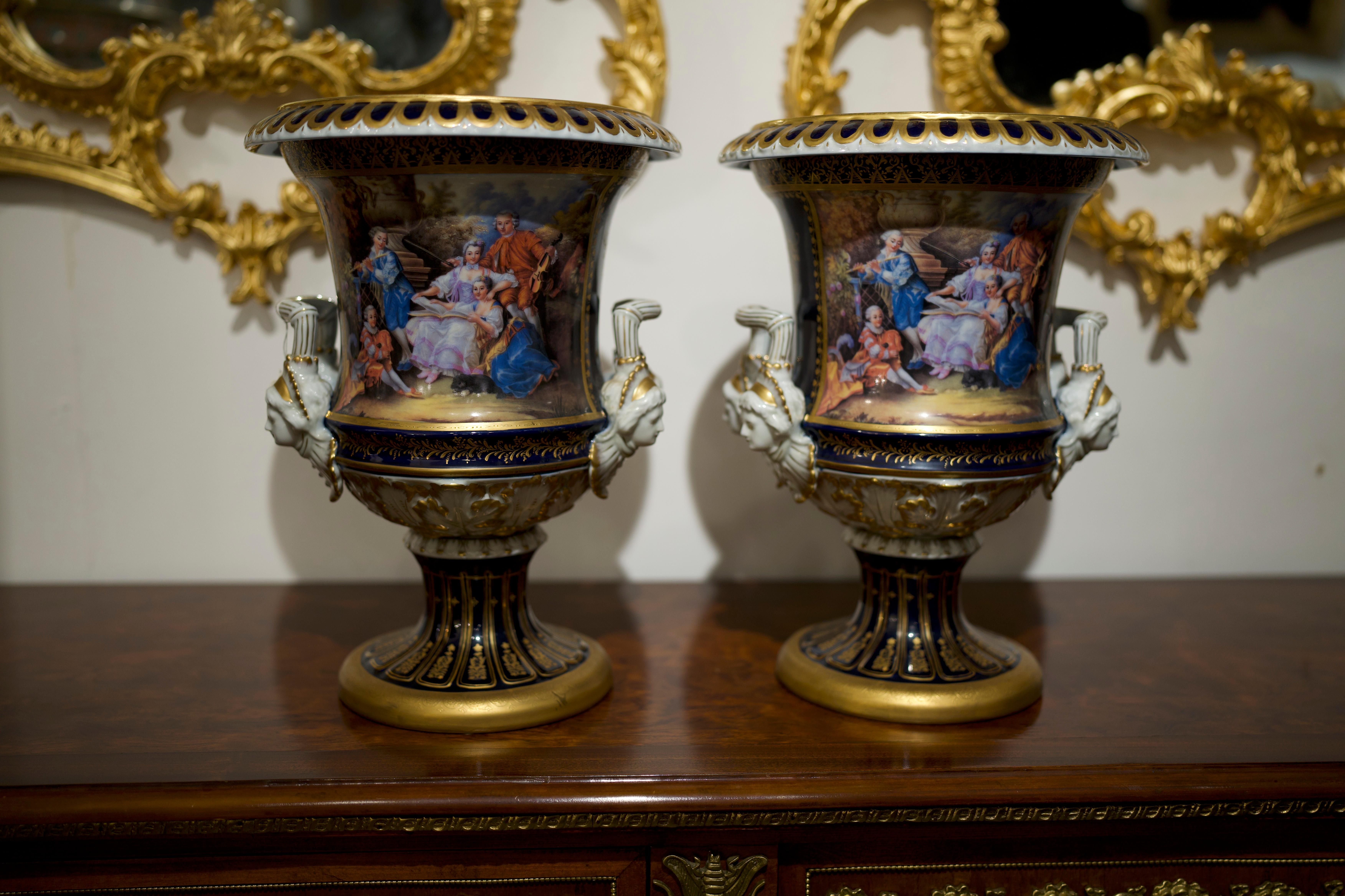 A very attractive pair of 19th century Royal Vienna porcelain urns. The Royal navy blue body highlights the wonderful hand painted cartouches on each side. Each depicting scenes of lovers boarded with beautifully gilded foliate details. This pair