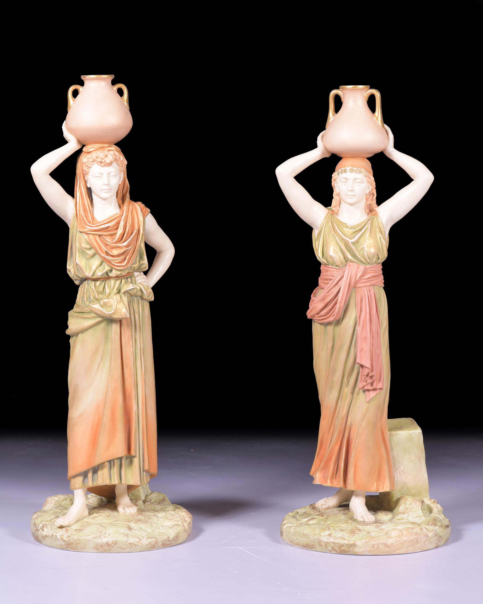 Modelled by James Hadley as women holding water vessels upon their heads, wearing long robes coloured in 'patent metallic' colours in shades of orange and green, upon rocky mound bases inscribed Hadley to the reverse, printed patent marks and shape