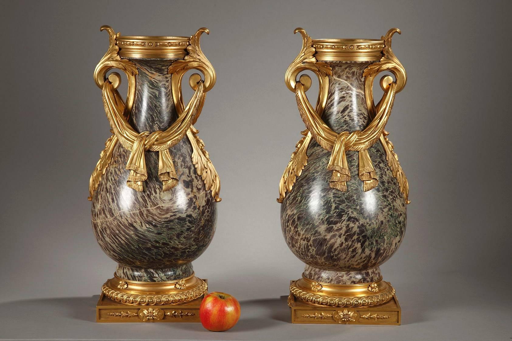 Pair of large, ornamental jasper urns from Russia with ormolu mounts. The handles are formed with scrolling acanthus leaves and they hold in place a piece of loosely tied drapery, which descends on both sides of the paunch. Each vase rests on a