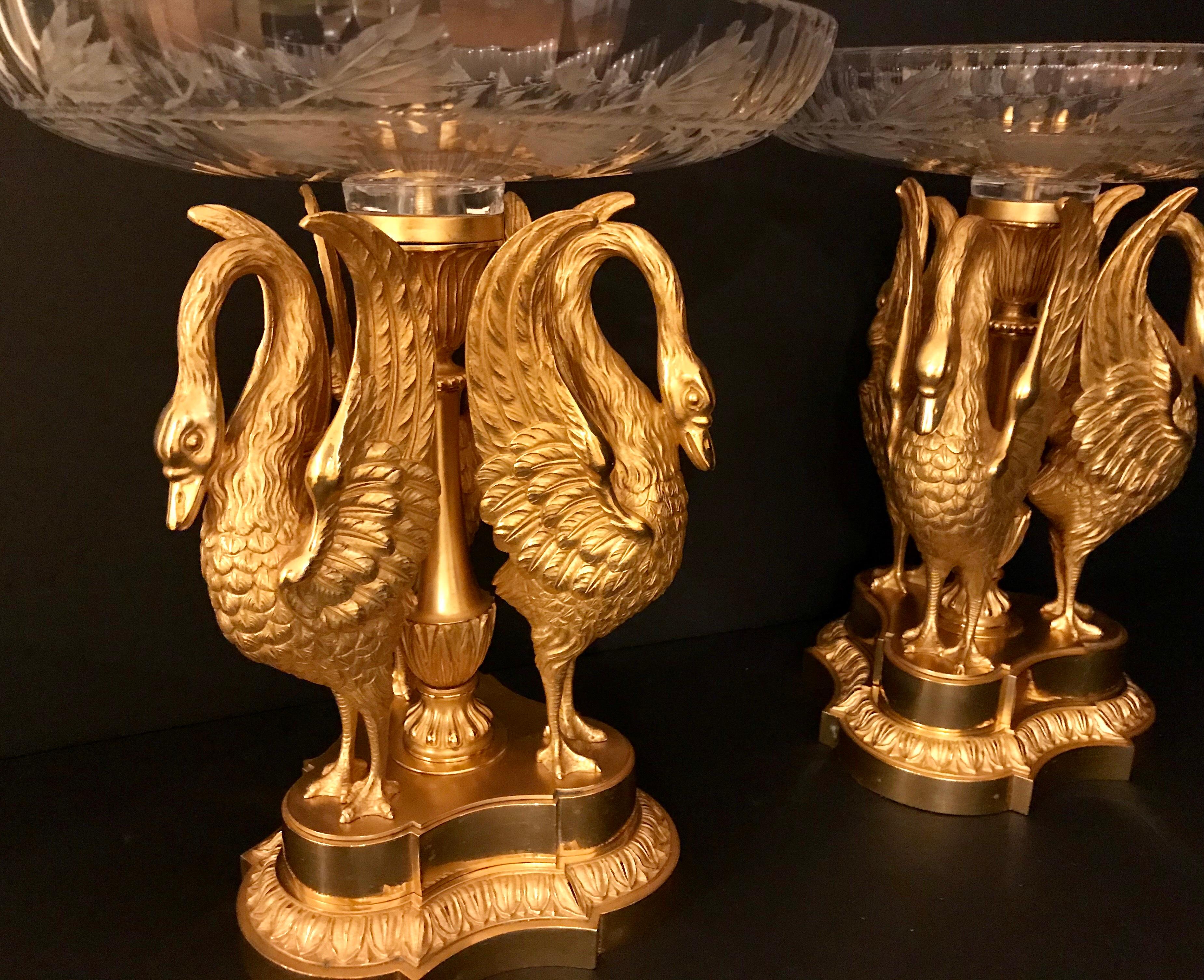 Magnifique paire de centres de table en bronze doré de Russie et cristal de Baccarat. Les tazzas amovibles de Baccarat, gravés d'un motif de couronne de laurier profondément taillé, reposent sur une sculpture en bronze doré de trois cygnes finement