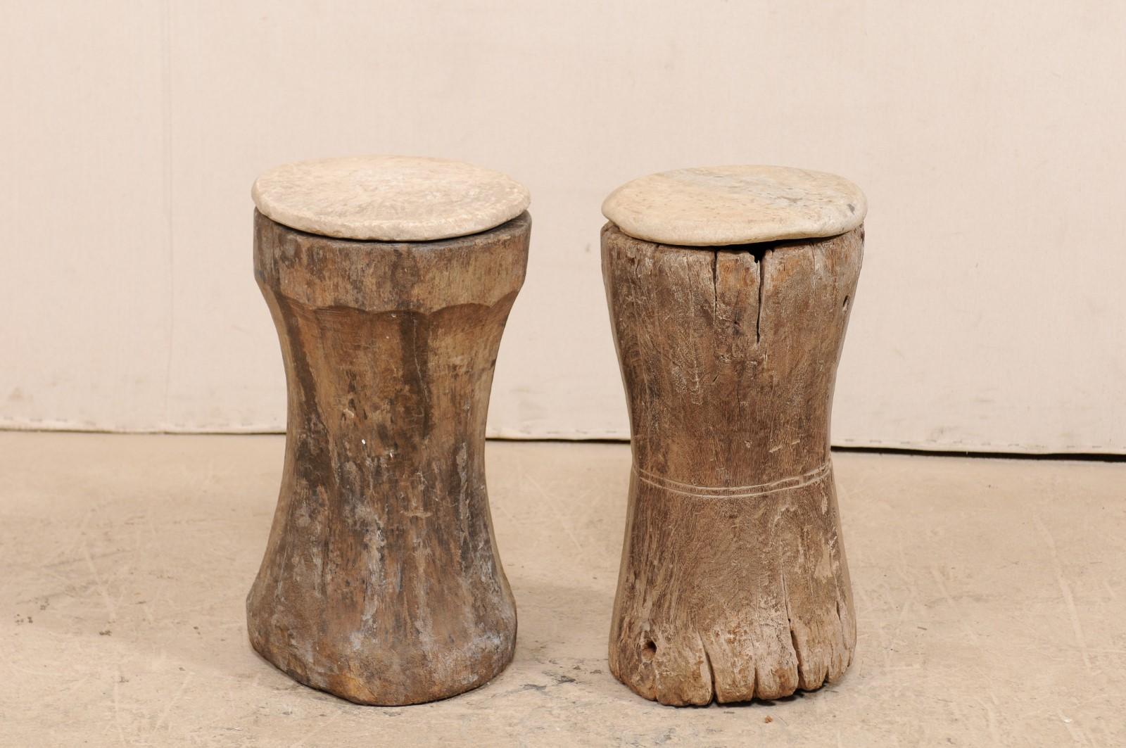 A pair of 19th century wooden mortar with stone top drinks or side tables. This unique pair of small-sized tables have been fashioned out of a pair of 19th century hand-carved wooden mortars from South Indian (Kerala), which have been topped with