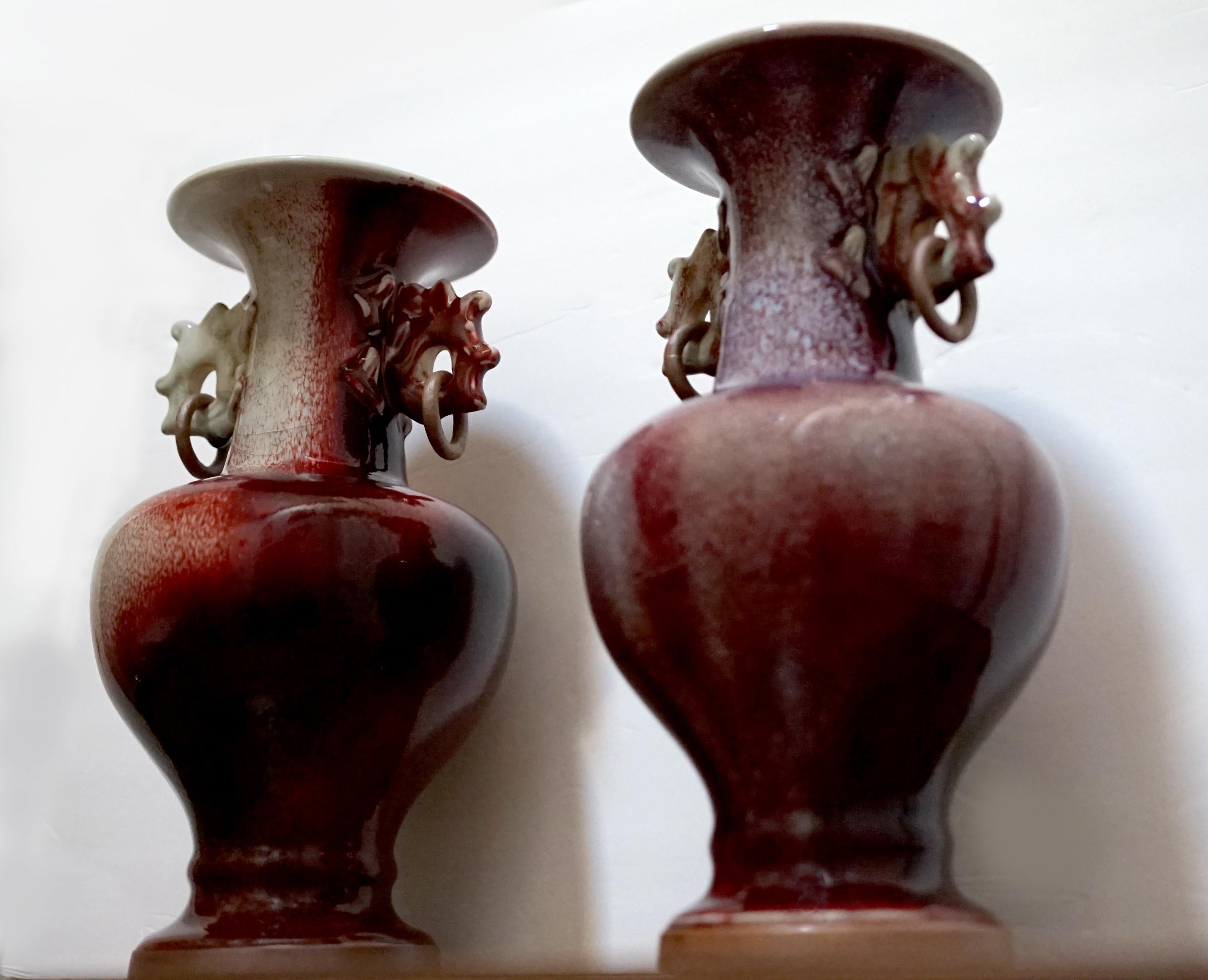 This wonderful sang de boeuf offering in deep red and turquoise travels as a pair. One of the most memorable features of the vases would be the intricate design of the ears with a copper ring and of course the colors. The oxblood is deep and
