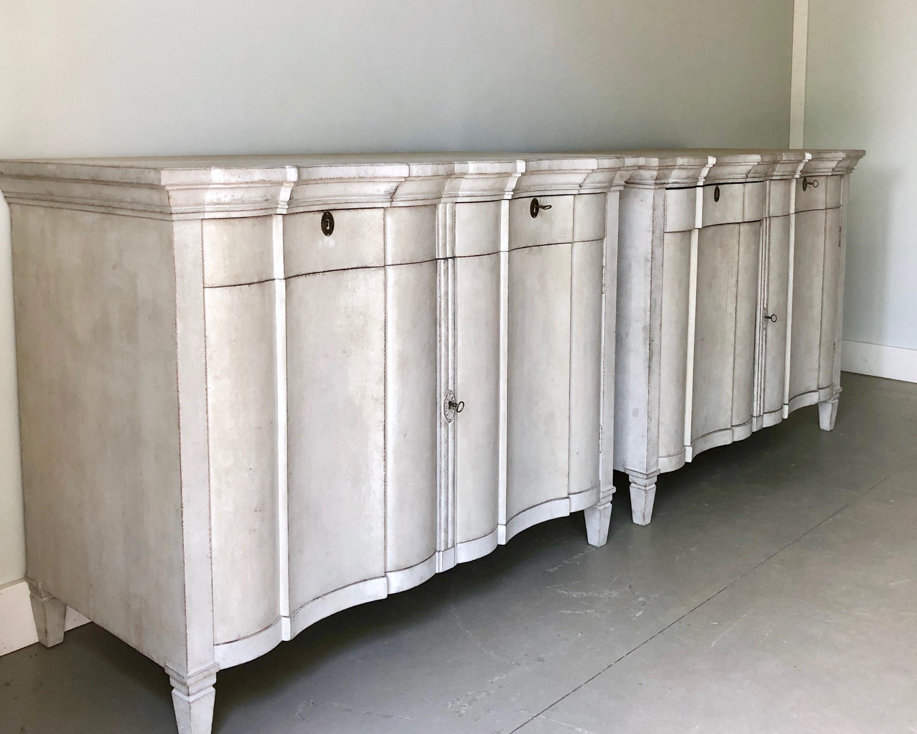 A pair of very curvy and large late 19th century Scandinavian sideboards in Rococo style painted in a soft white with two drawers under the shaped top and plenty of storage inside, resting on short tapered and fluted feet.