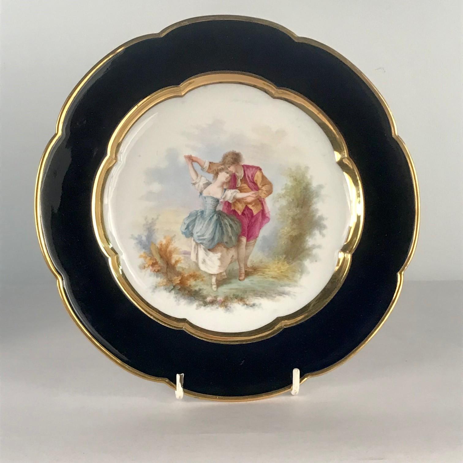This pair are painted with lovers in a romantic and rustic landscape. There are two Scenes Gallantes: dancing in one, resting by a fountain in the other, a small dog perhaps emblematic of faithfulness begs in the background. Each plate is gilt,