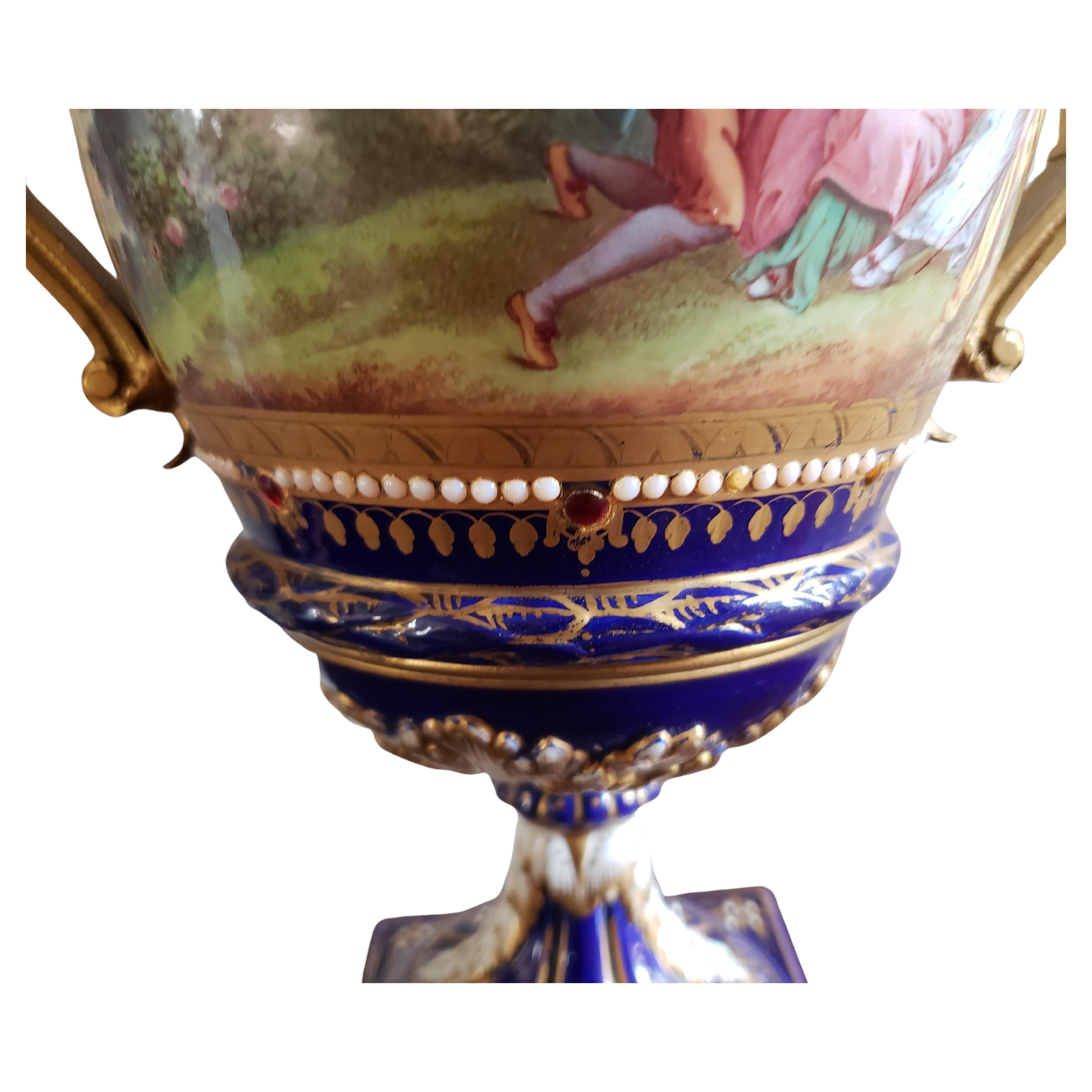 Paire d'urnes à deux anses en porcelaine de Sèvres du 19ème siècle, peintes à la main et décorées de cobalt et de dorure, en bon état. Scènes différentes peintes à la main sur chaque face. Aucune fissure ou réparation. Juste une usure normale
