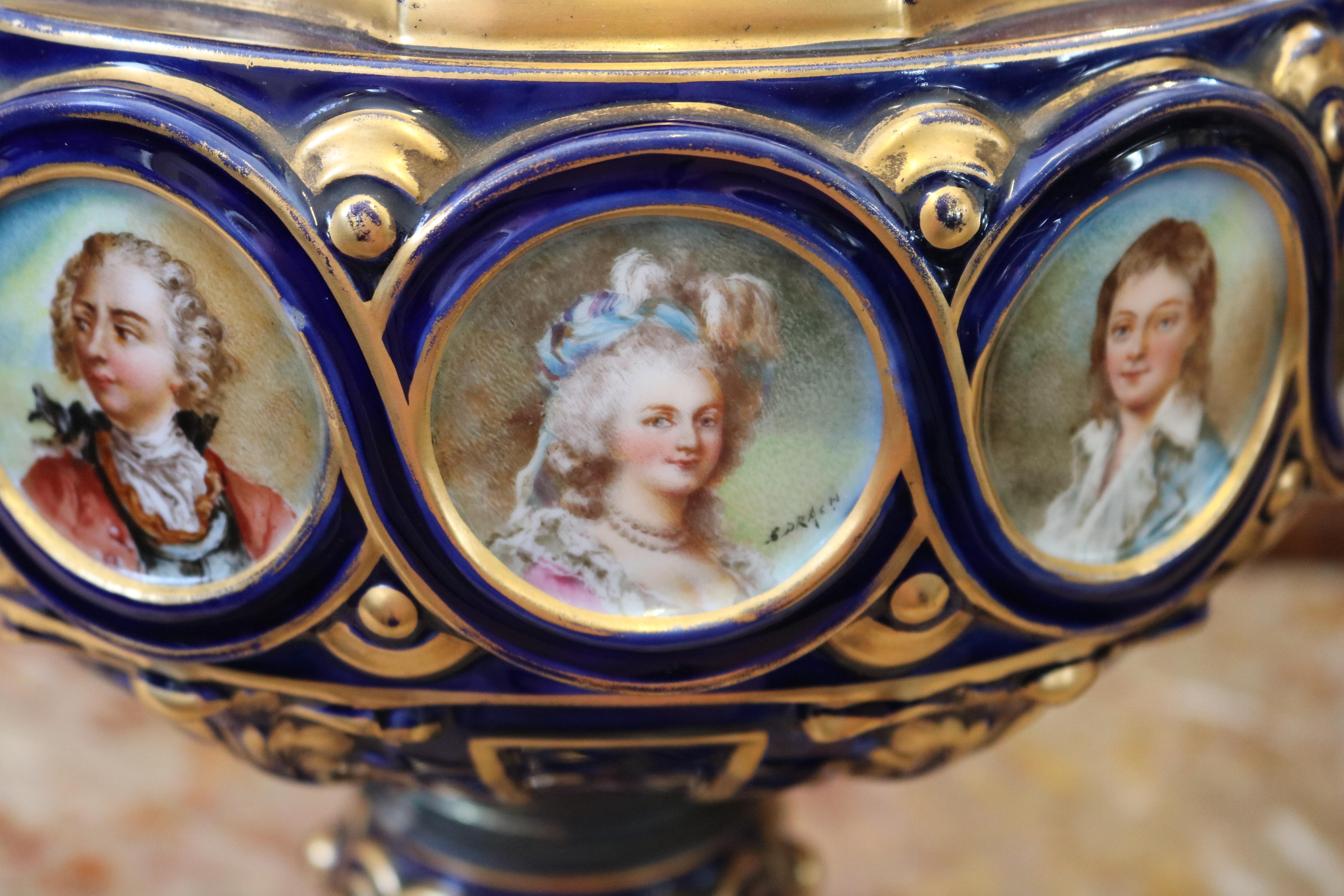 These vases were made in France in the late 19th century and are modeled after the Sevres vase Grec A Ornements with painted royalty around the rim of each. The vases are gorgeously paint decorated and the form is stunning. These vases both have