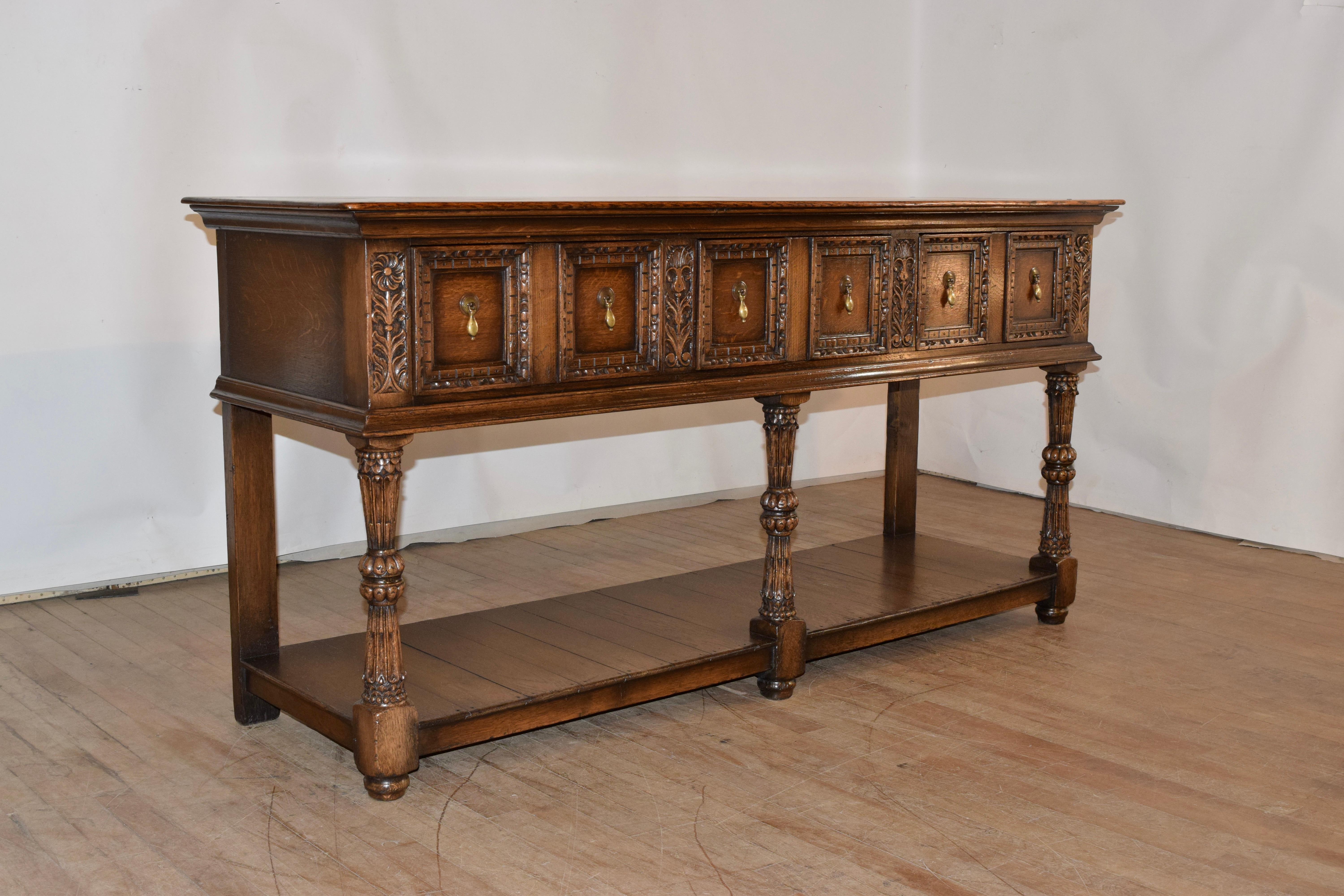 Pair of 19th century English oak sideboards with  plank tops following down to simple sides and three-paneled and carved drawers in the front, flanked by floral carved panels over a molded edge. The pieces are supported on three wonderfully carved