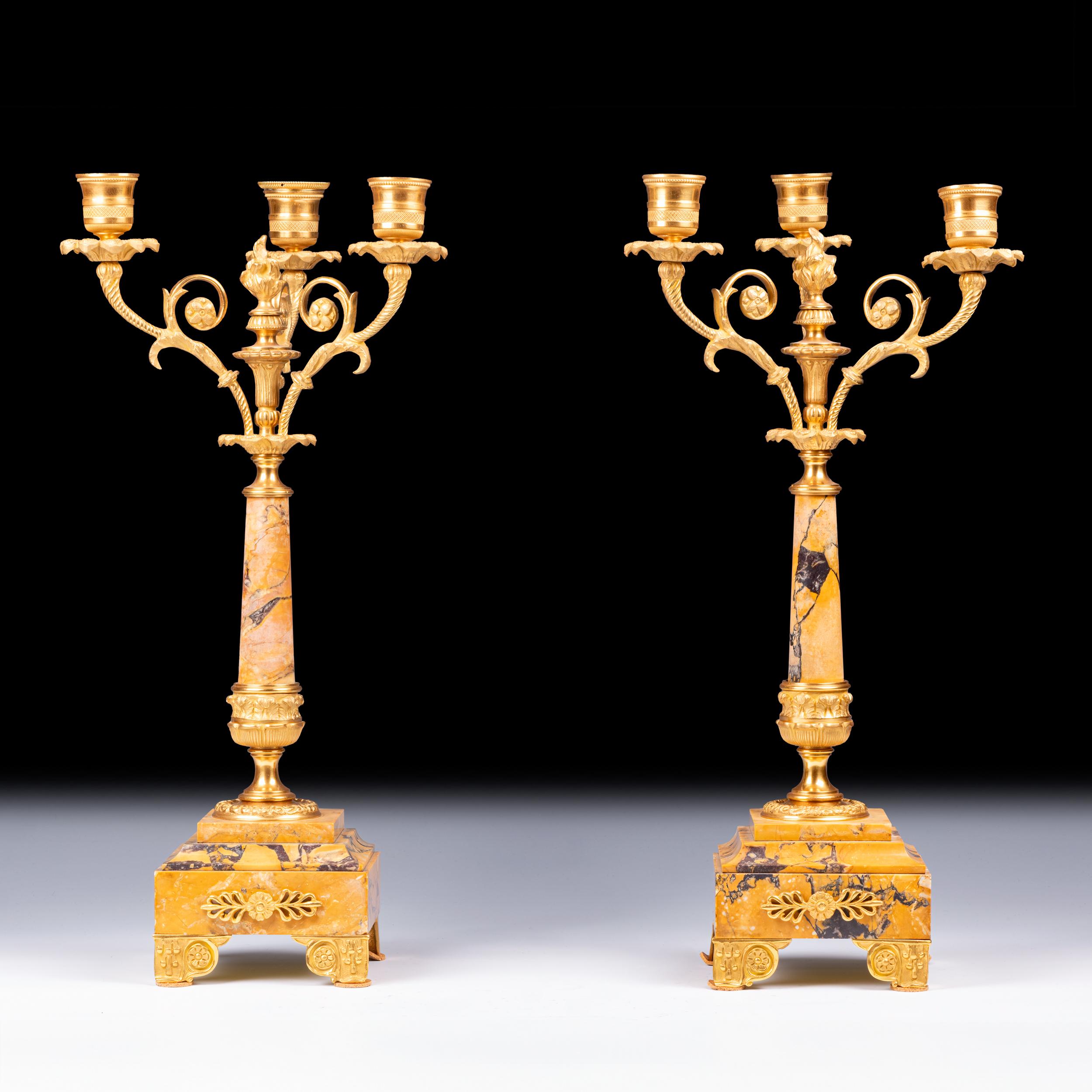 Bellissima coppia di candelabri francesi del XIX secolo in marmo di Siena e ormeggio, ciascuno con tre candelabri decorativi a foglia scopertasi sopra un supporto centrale circolare affusolato in marmo, montato con un terminale a fiamma, che termina