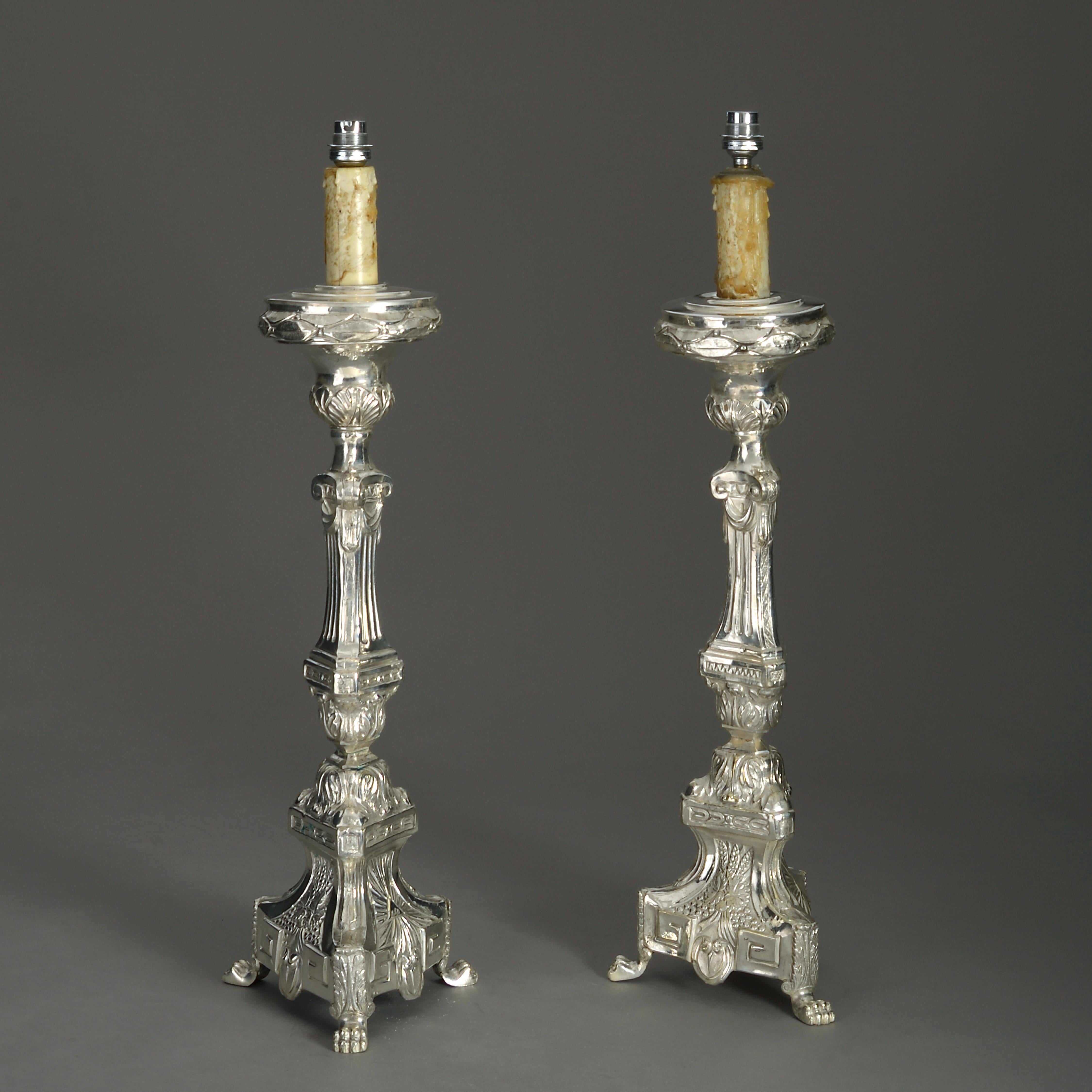 A tall pair of 19th century silver plated pressed metal candlestick lamps in the Baroque manner, now mounted as table lamps.

Wired for electric lighting according to UK safety standards.

This piece can be rewired for US, EU and worldwide