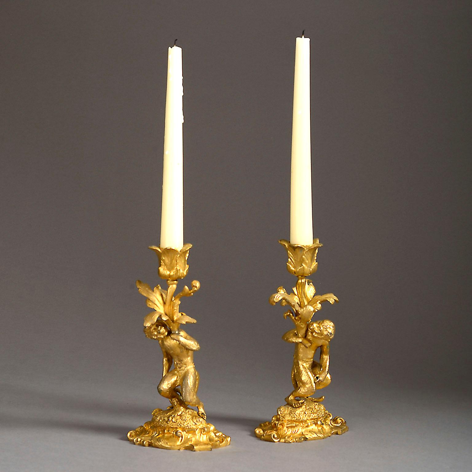 A pair of 19th century singerie ormolu candlesticks modelled as monkeys standing on elaborate Rococo bases and holding bunches of foliage issuing the leaf-cast candle nozzles. Signed F.P to the base.
The form of the present pair of candlesticks is