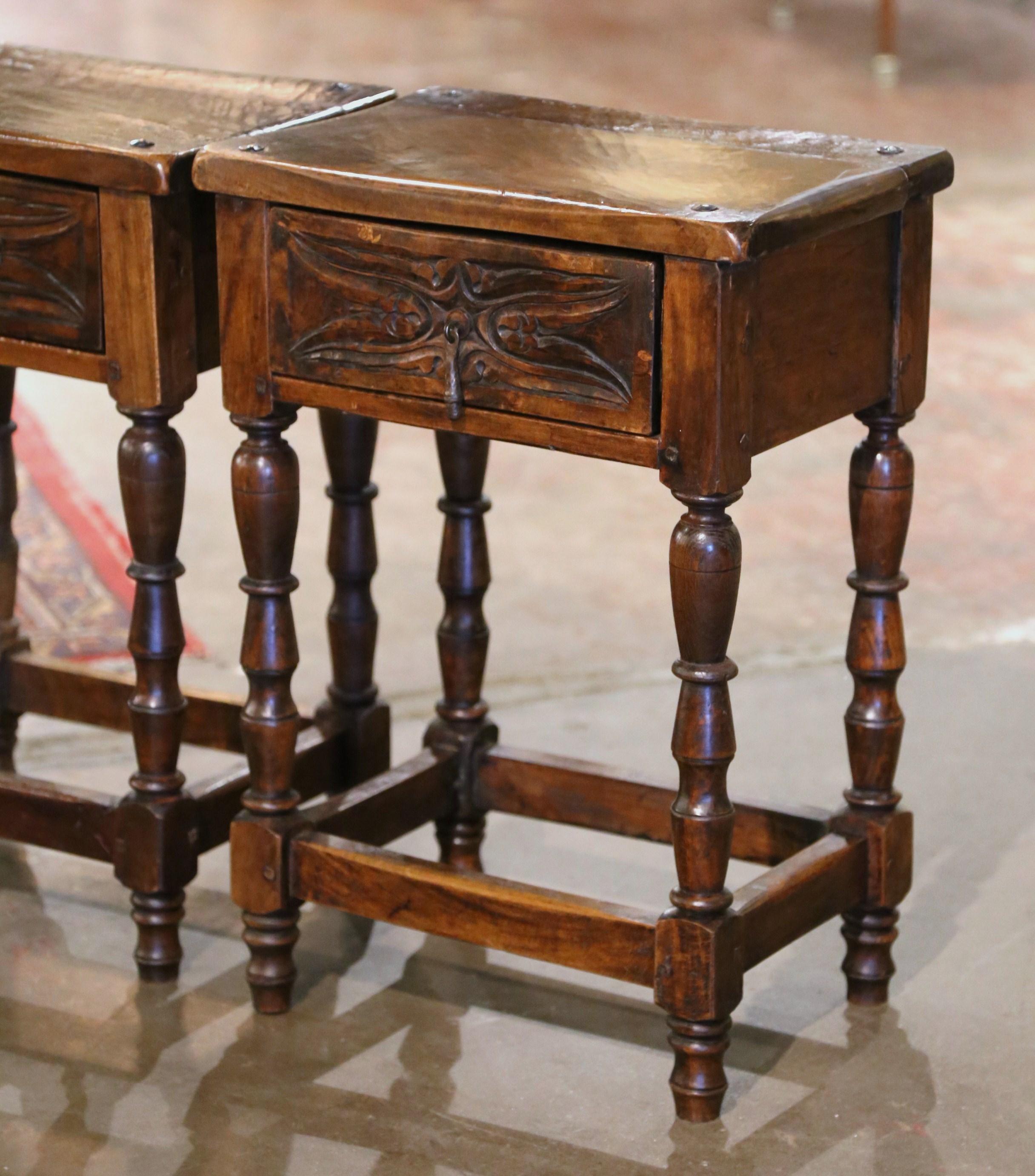Decorate a den or a living room with this elegant pair of antique side tables. Crafted in Spain circa 1880, each table stands on turned legs joined with a bottom stretcher. The Baroque table features a center carved drawer, embellished with
