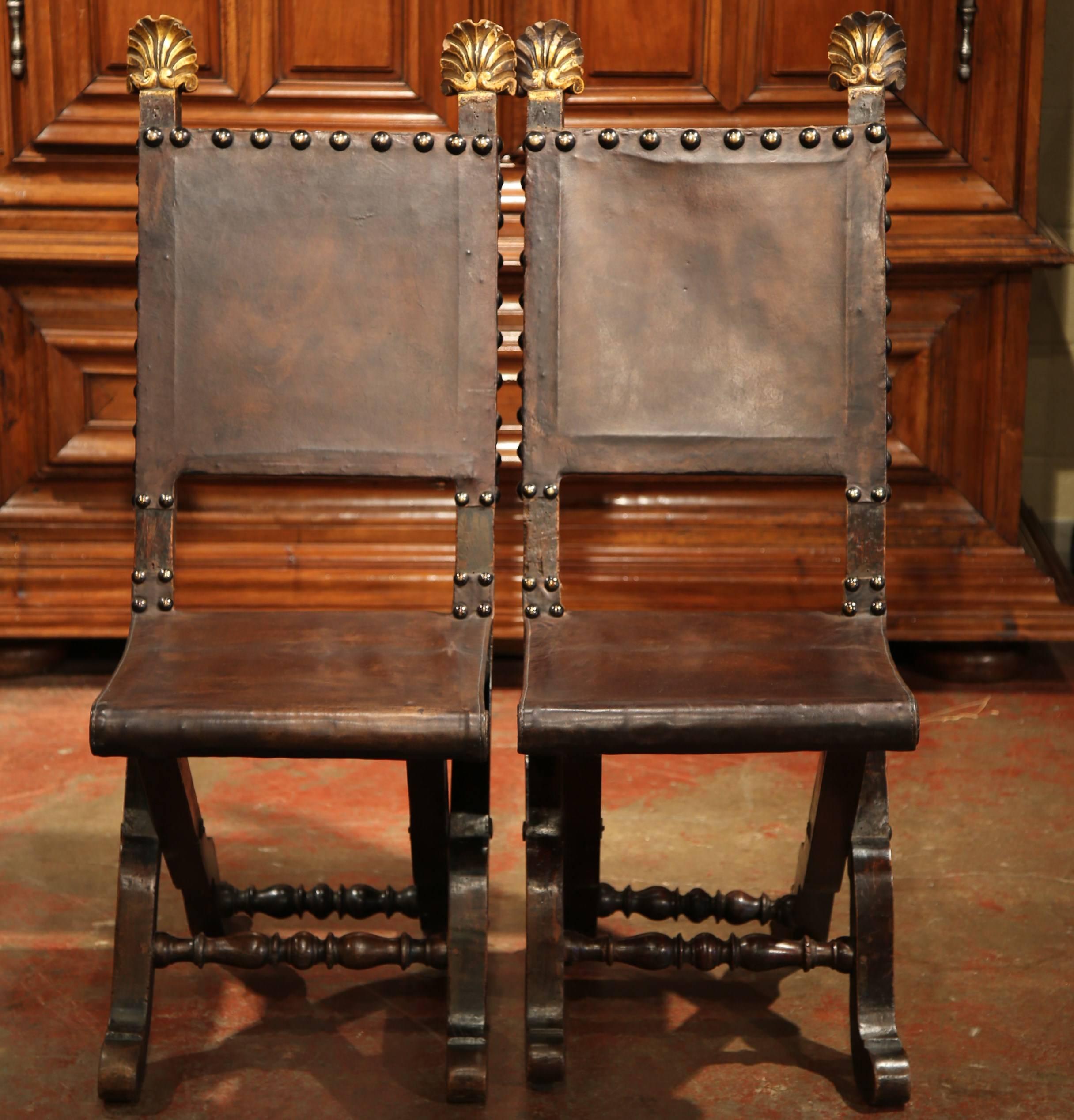 This elegant pair of antique fruitwood side chairs were crafted in Spain, circa 1820. The versatile, folding chairs have a simple shape and feature their original brown leather seat coverings. The chairs are embellished with decorative brass