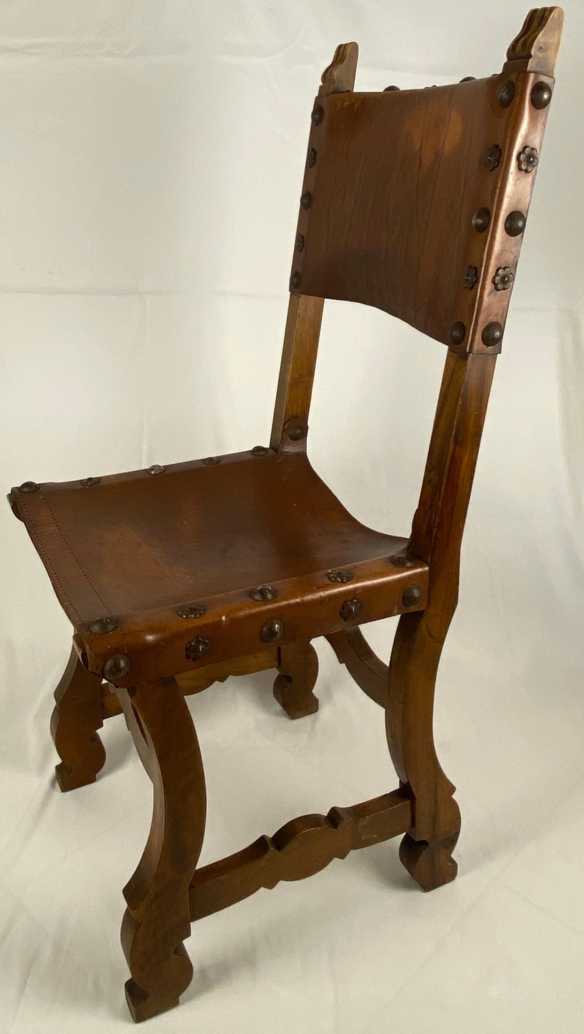 A wonderful pair of 19th century Spanish colonial dining chairs or side chairs, Baroque style leather and walnut side dining chairs, circa 1890s. Original leather backs and seats accentuated by large brass nailhead trim. Supported by two front