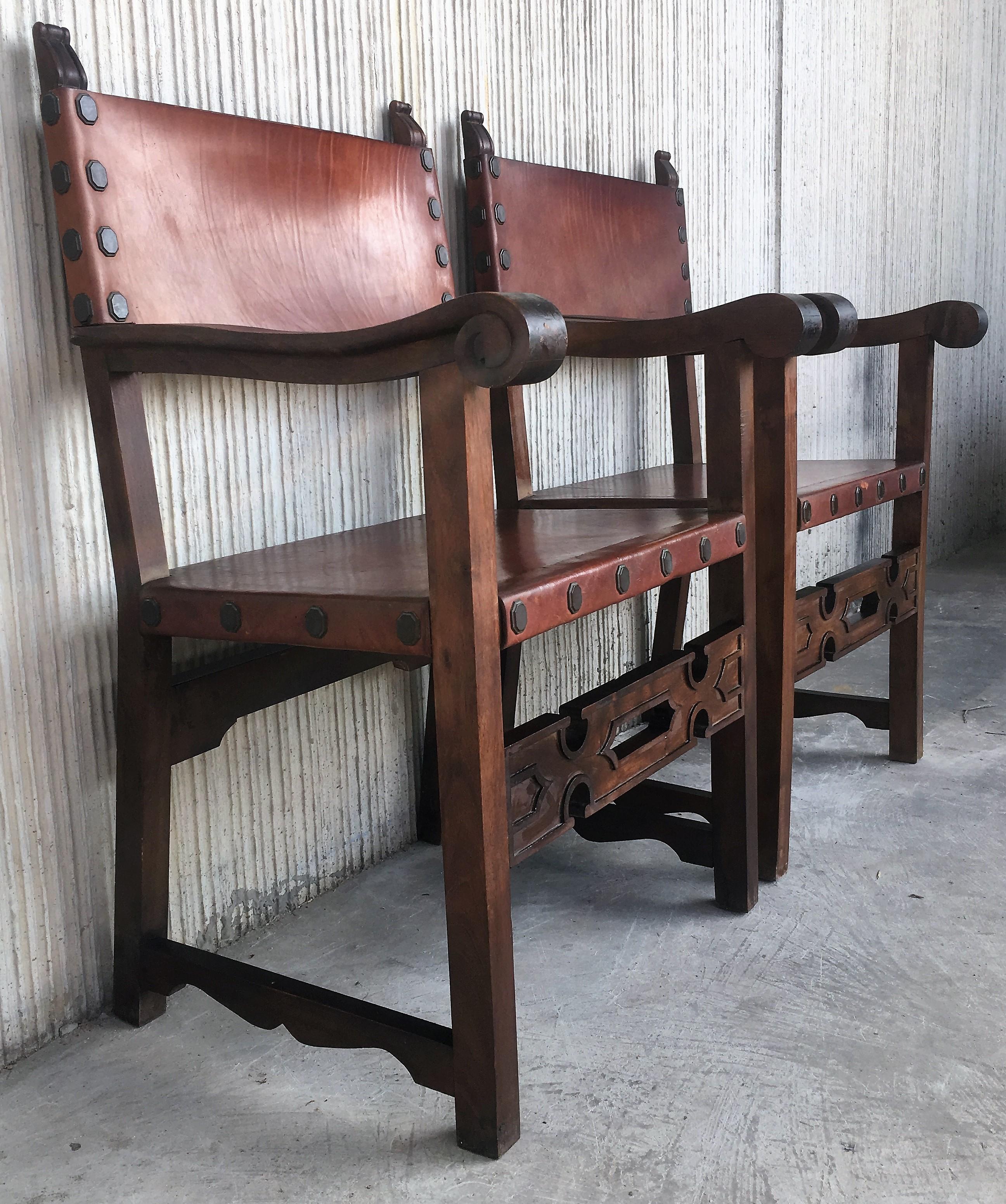 Pair of Spanish colonial style armchairs, having leather both seats and backs, and brass nailheads.

