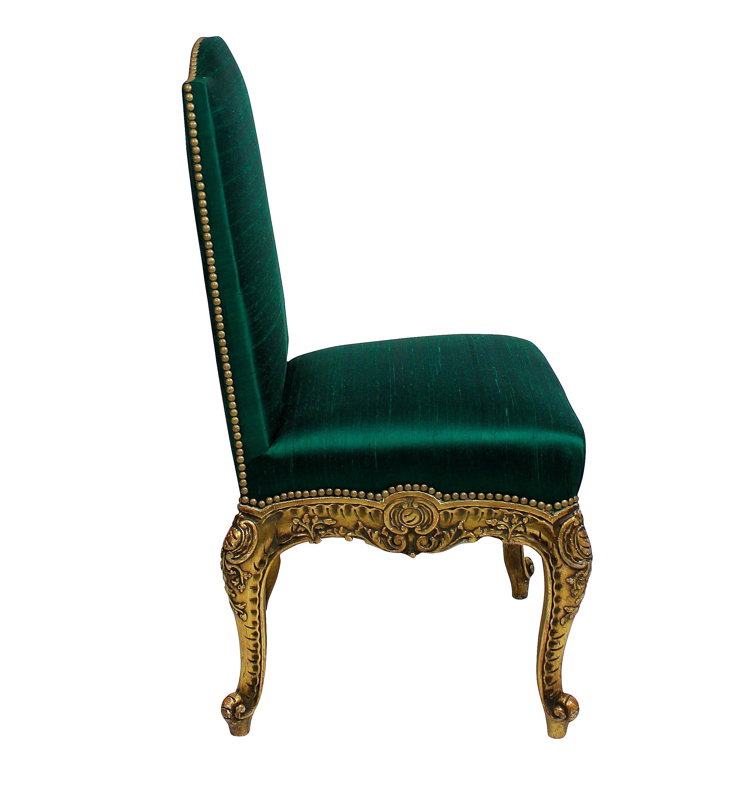 A pair of Spanish carved giltwood side chairs with cabriole legs and newly upholstered in emerald silk with gold studding.
    