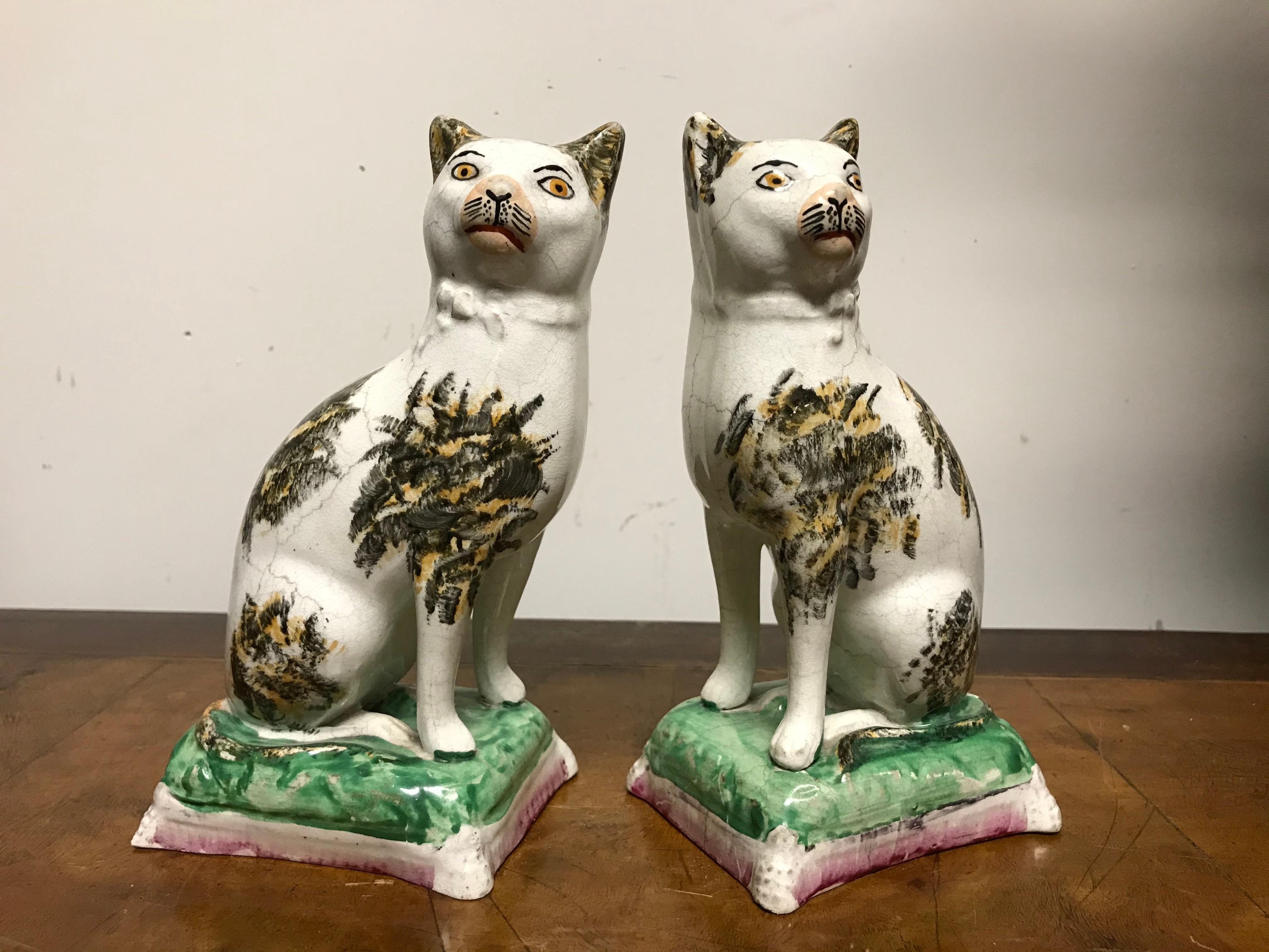 A wonderful pair of early 19th century Staffordshire glazed pottery cats shown seated on fancy pillows. Something about the quizzical looks on their faces makes this charming pair all the more appealing.