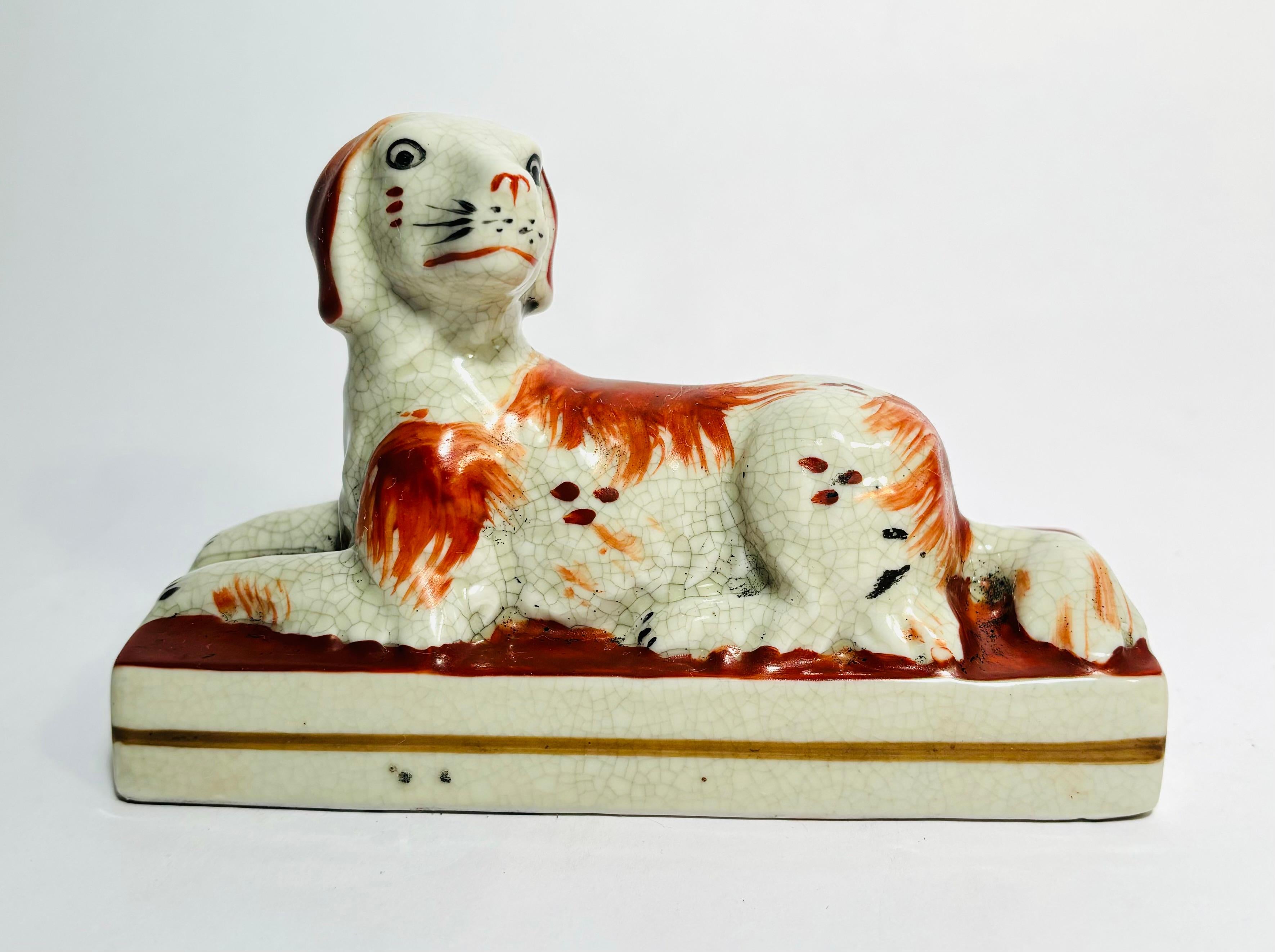 A pair of finely molded and hand painted English Staffordshire dogs. This pair features full body reclining hounds with the most charming of hand painted faces and colors. On their own 