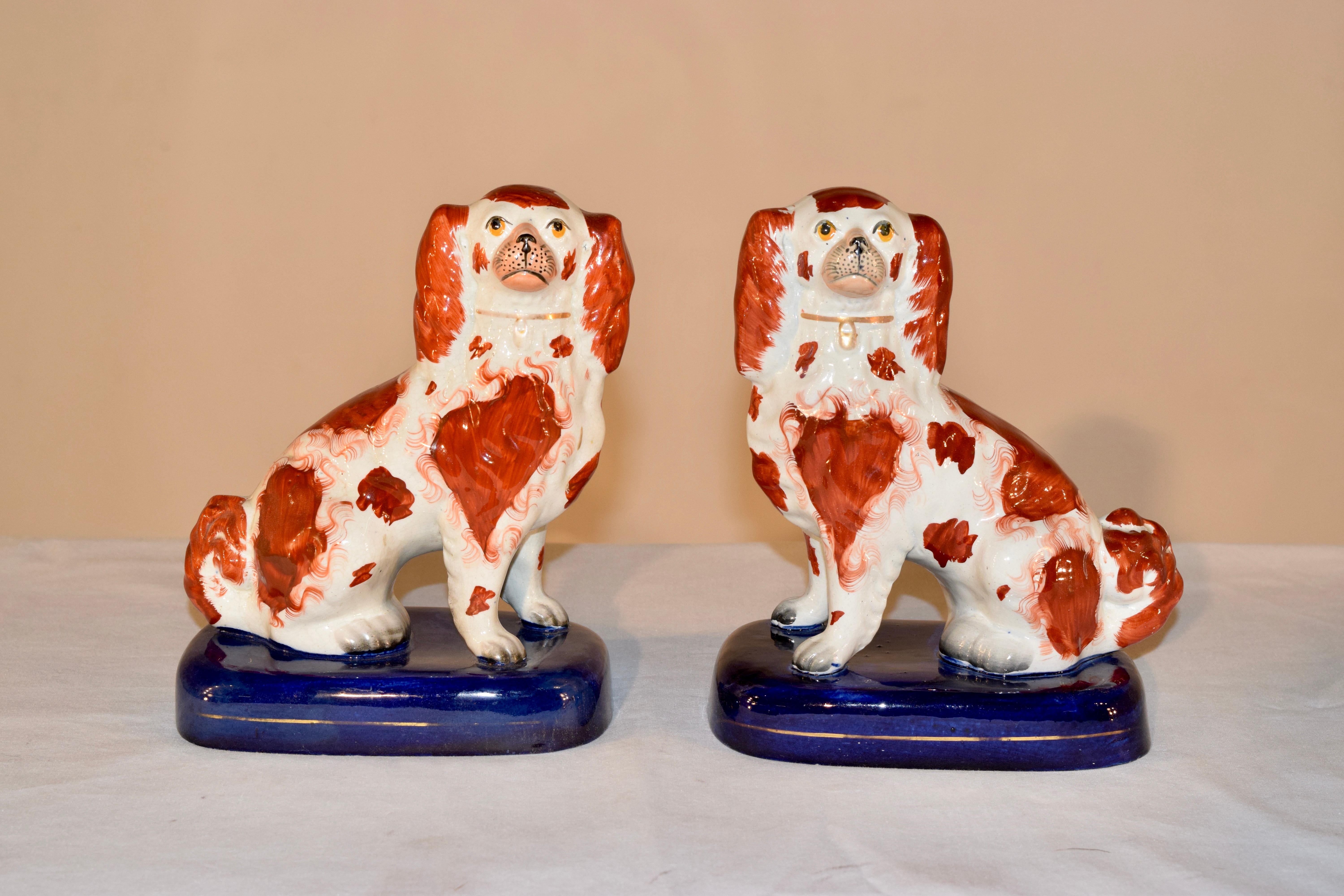 Ein Paar Staffordshire-Spaniels aus dem 19. Jahrhundert in Rost und Weiß auf blauem Sockel. Die Spaniels haben getrennte Vorderpfoten. Sie sind wunderschön geformt.