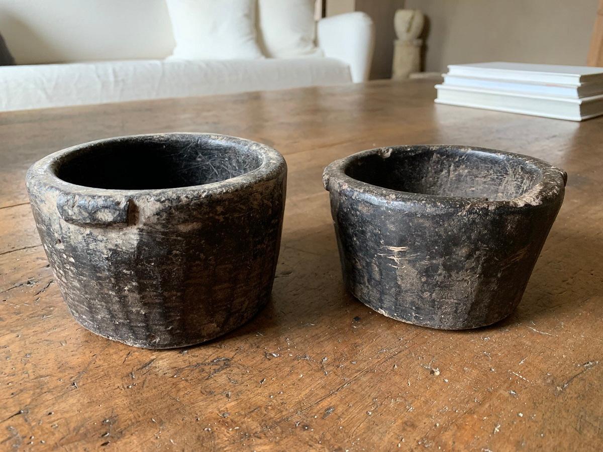 A pair of small mortars. Hand carved in Asia in a hard black stone probably schist. These kind of small vessels have been made for centuries in Asia. These ones most likely are 19th century Nepalese examples.