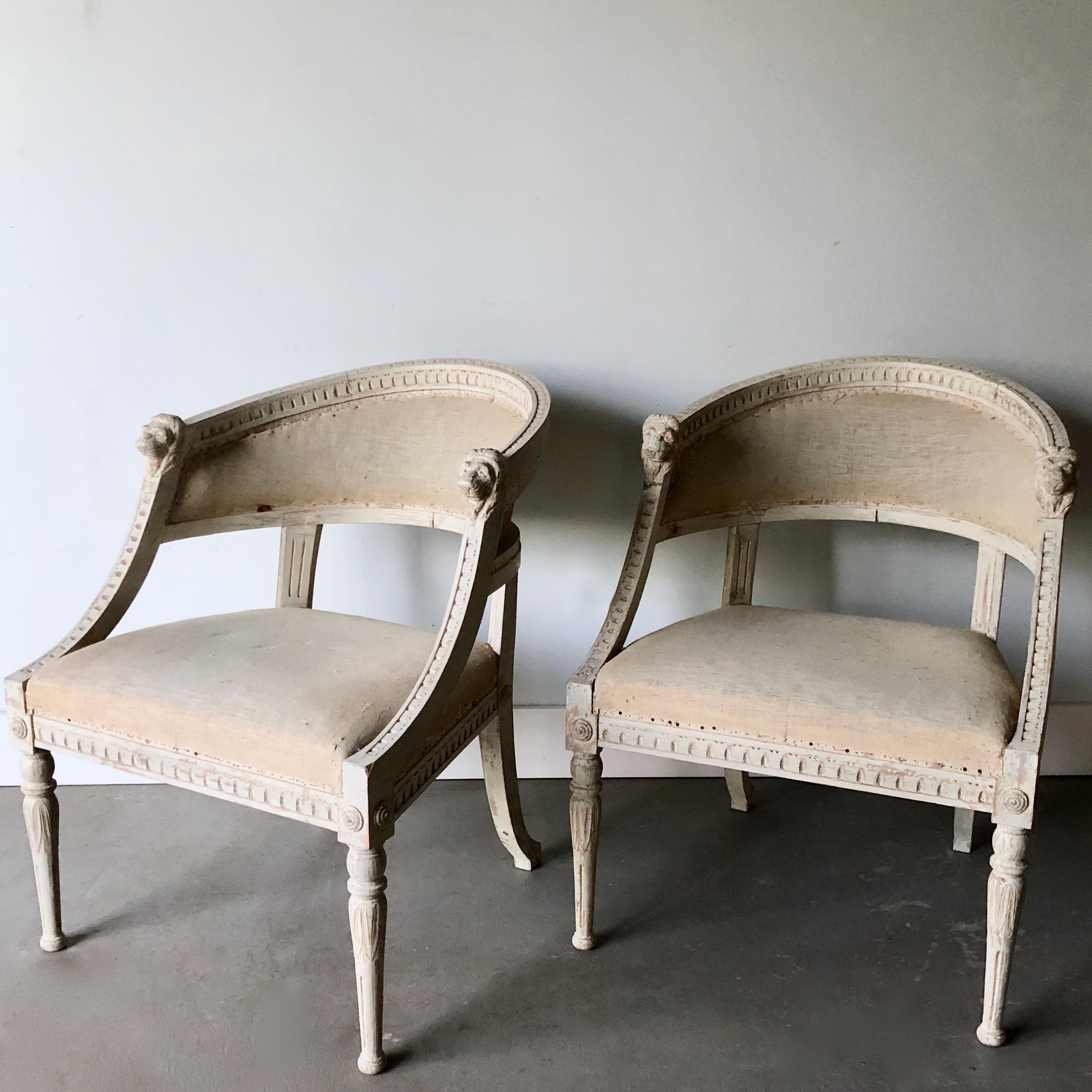 Pair of 19th century barrel back chairs, Sweden circa 1890, with rounded form, detailed lions' head carvings on hand rest and slender tapered legs original worn cream/ white paint finish and padding, ready to your own choice of fabric. More than