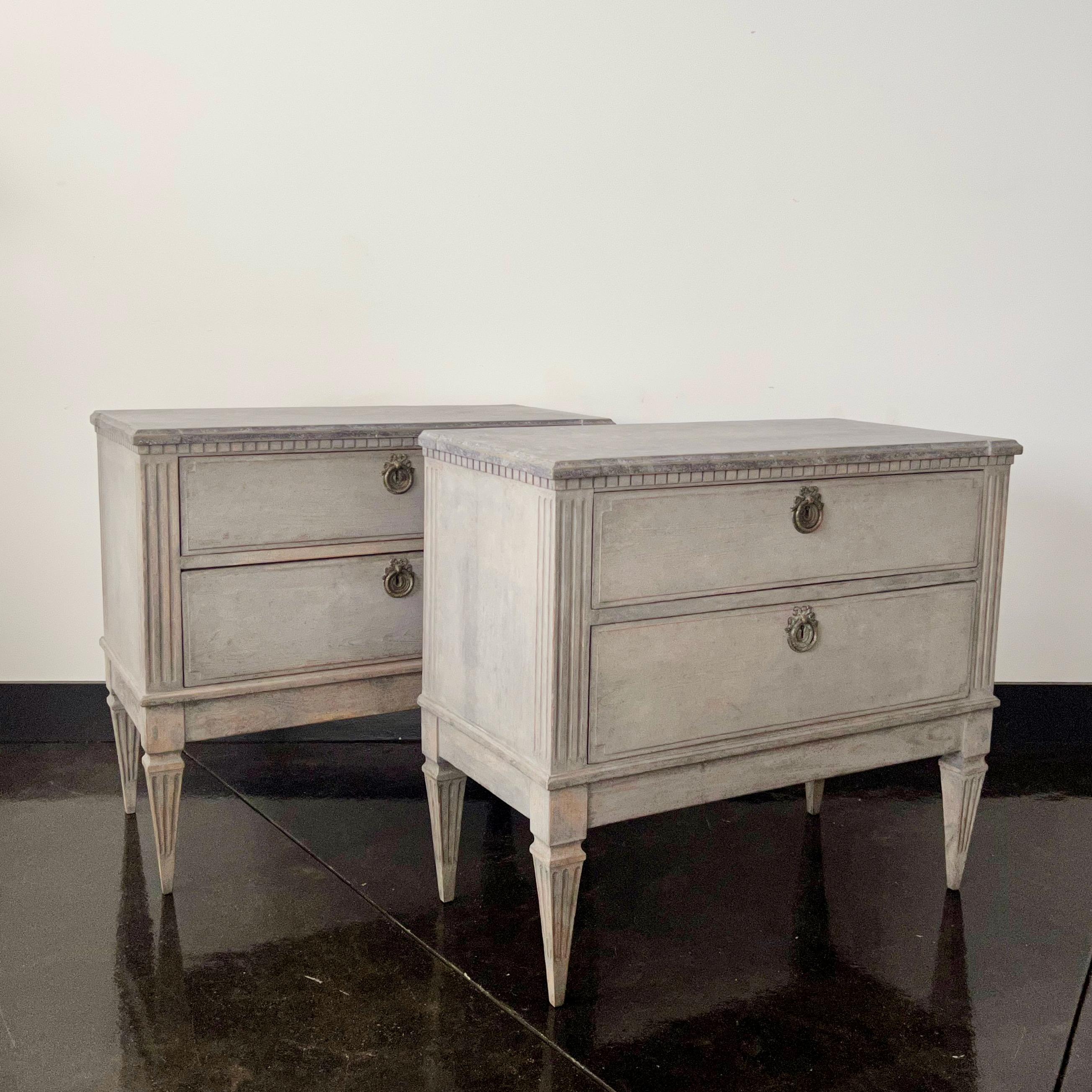 A pair of early 19th century Swedish period Gustavian chest of drawers with brass fittings, shaped marbleized wooden tops, canted and fluted corners posts in light blue finish and darker blu/gray top. 
Sweden, circa 1810.
More than ever, we