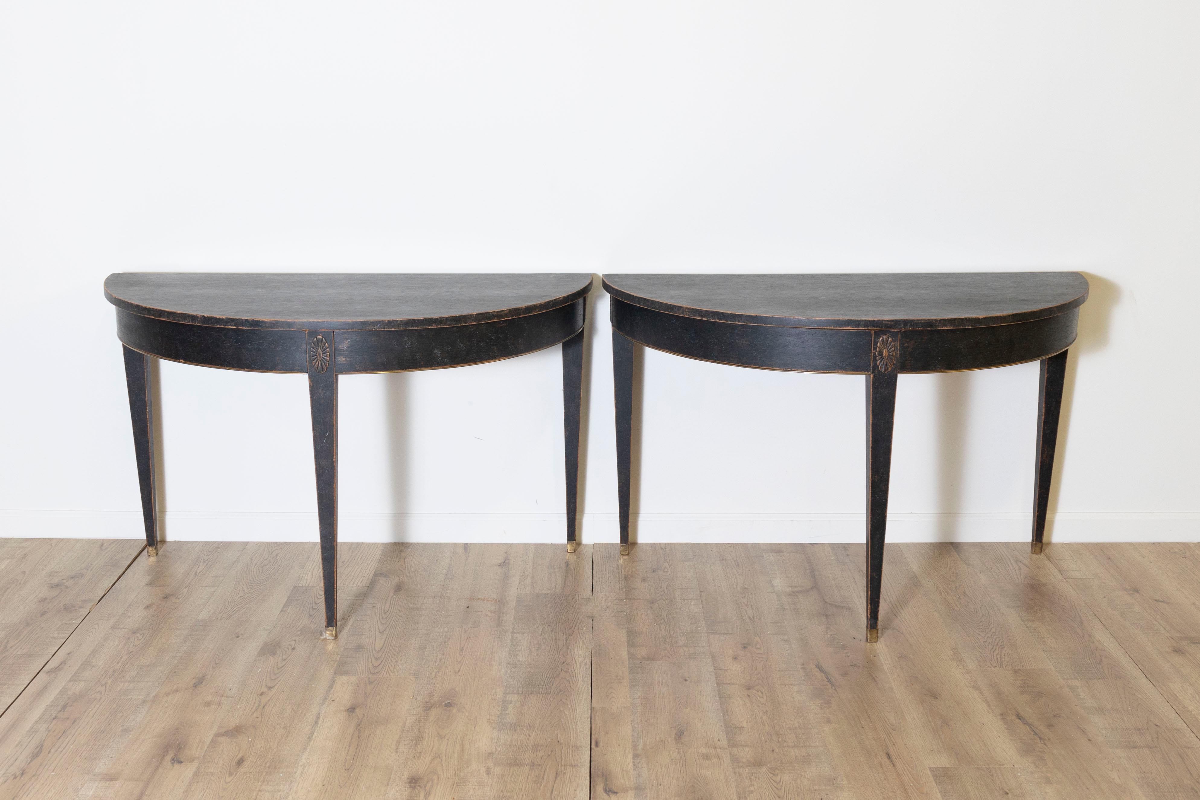 This pair of 19th-century Swedish demi-lunes, circa 1800, perfectly captures the elegance and simplicity of Neoclassical design. Crafted from pine and finished in a sleek black patina, these side tables feature the signature half-moon shape, ideal