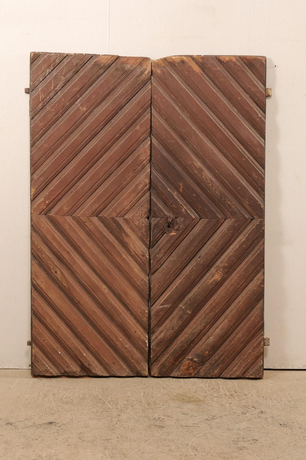 A pair of Swedish doors with geometric patterns and original paint from the 19th century. This pair of antique doors from Sweden feature a repeating diamond pattern, comprised of a smaller diamond being made up where doors join when closed, at