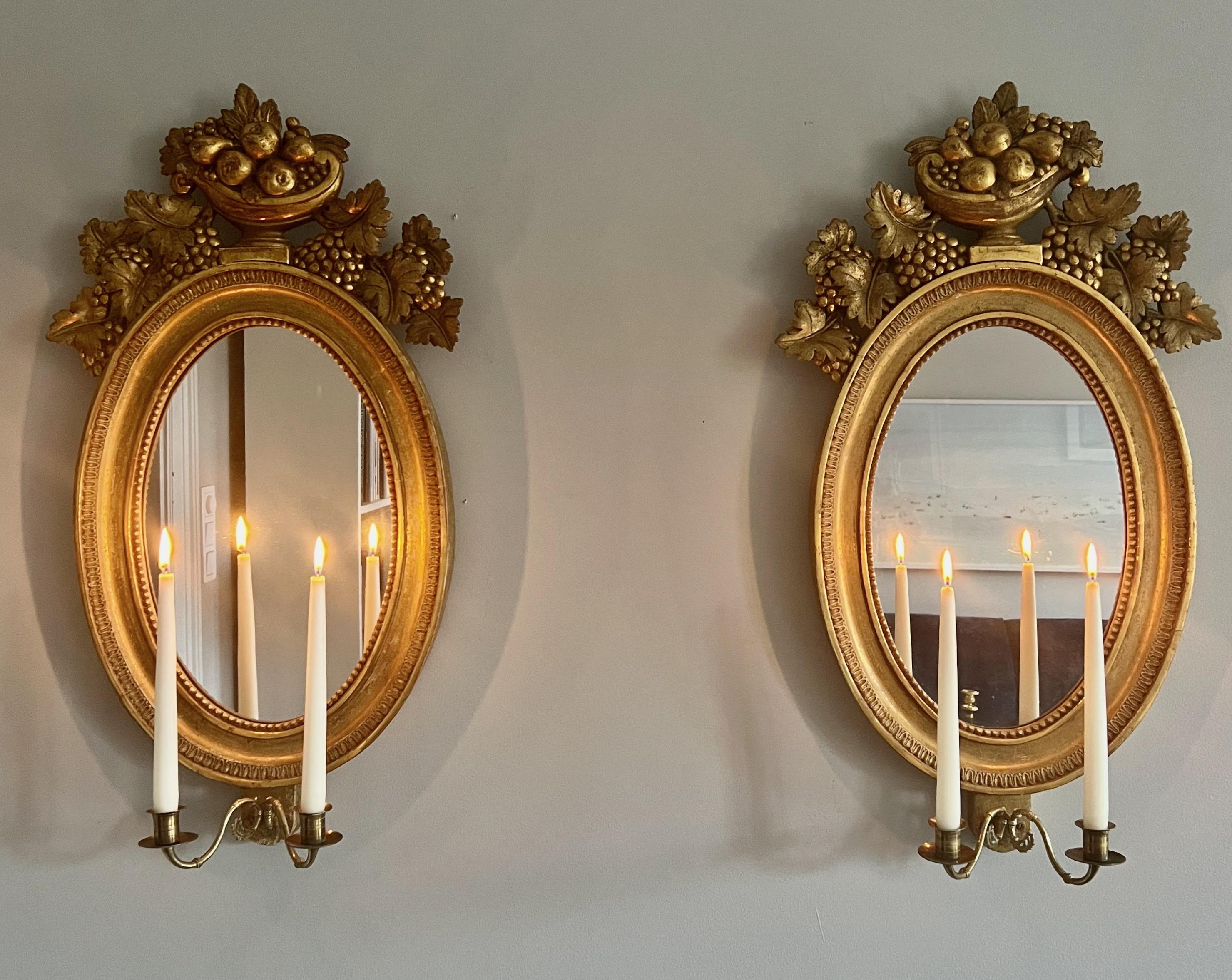 A very fine pair of 19th century Swedish girandole mirrors in carved giltwood by Petter Gustaf Bylander (1777-1859), Gothenburg, Sweden. They have their original gilding with a beautiful worn surface patina. The bronze candleholders are original