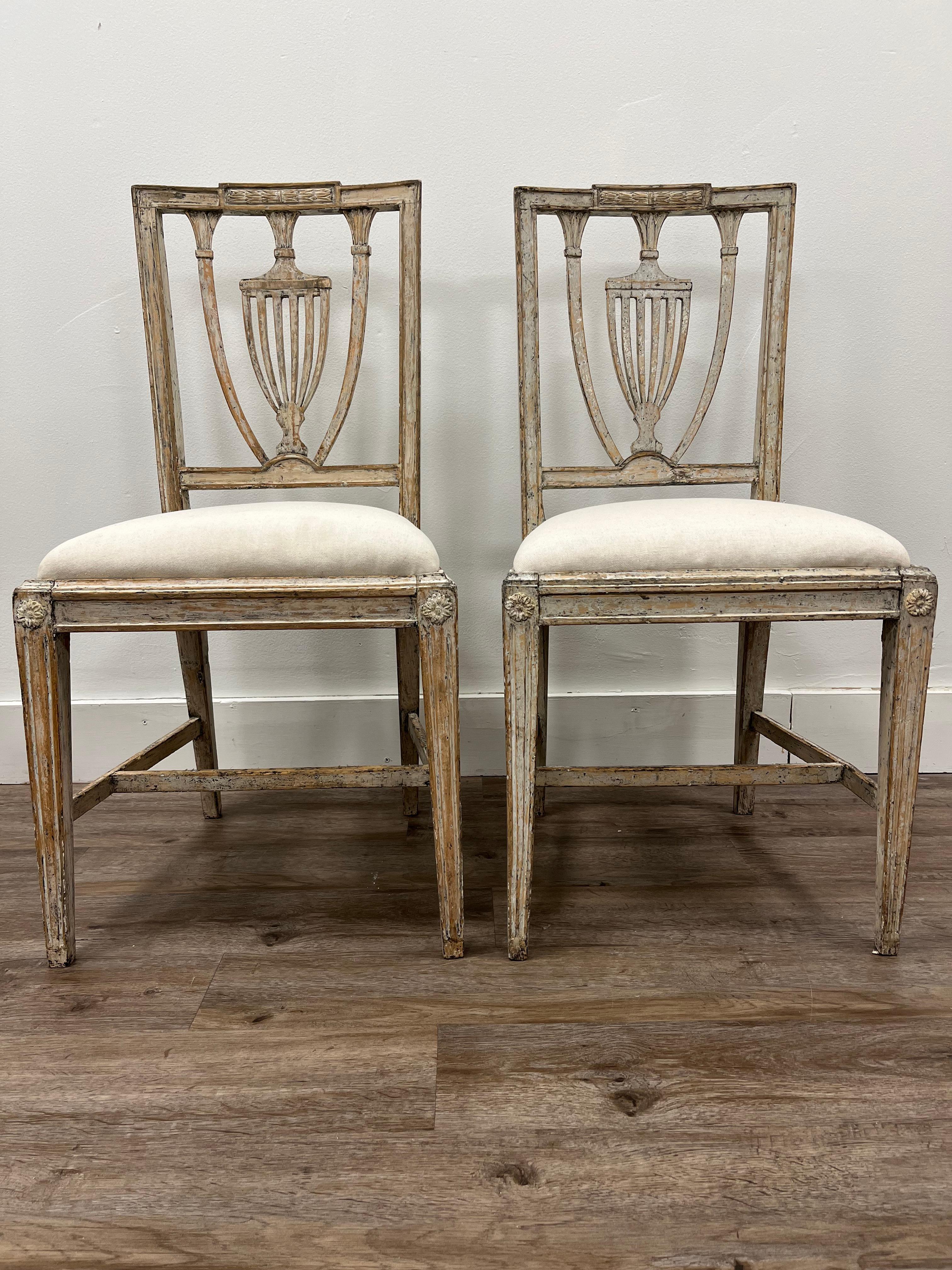 A pair of Swedish Gustavian chairs made in Stockholm by master craftsman Melker Falkberg (1746 - 1822). Stamped with Stockholm chairmaker's seal and maker signature. Scraped to their original pale grey color. Original slip seats are reupholstered in