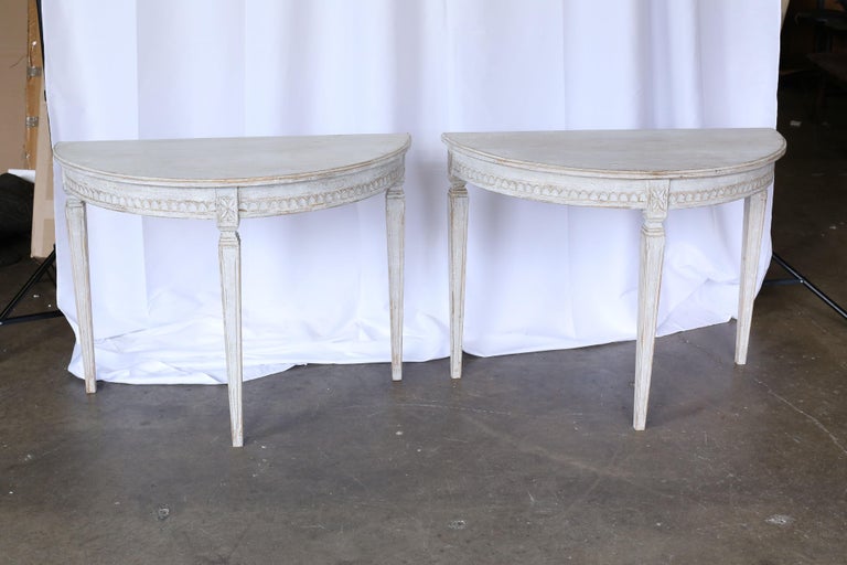 Pair of 19th century Swedish Gustavian demilune tables with carved detail above each leg and a carved detail around the apron.