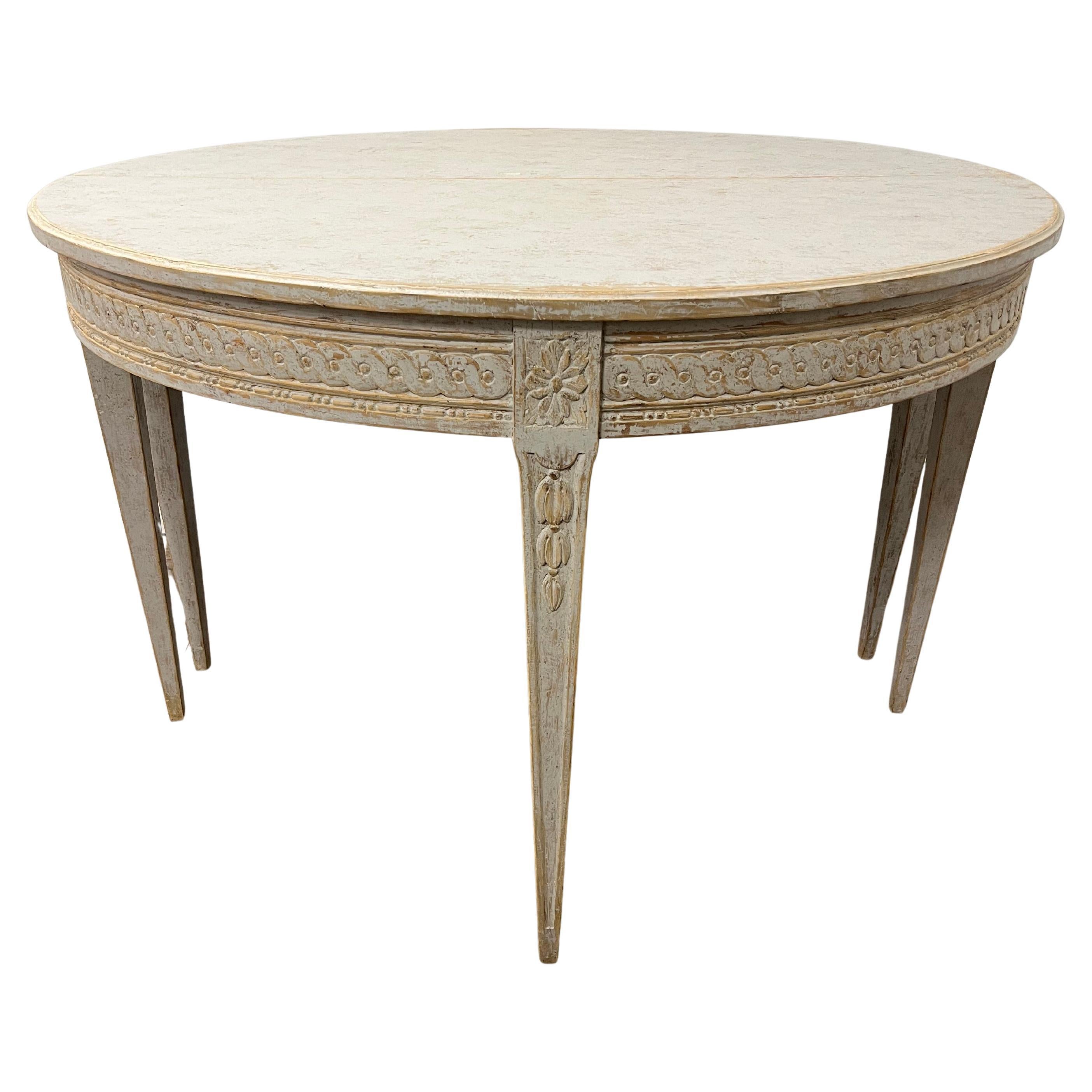 Paire de tables démilunies de style suédois gustavien, ornées d'un décor sculpté à la main en guilloché. Les rosettes reposent sur des pieds fuselés sculptés à la main. Cette pièce a été peinte à la main avec goût en blanc tendre. Les demilunes