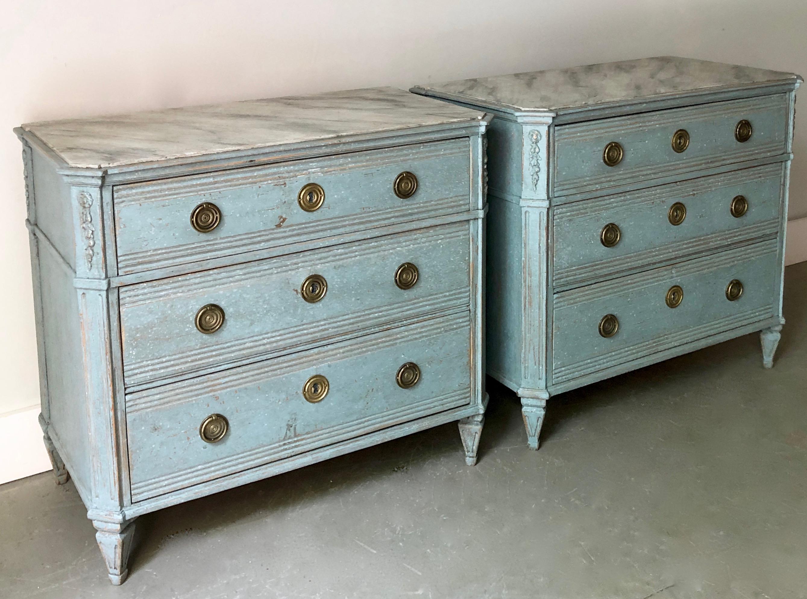 A pair of 19th century Swedish Gustavian style chests with marbleized wooden tops. Drawers with raised panels and bronze hardwares. Canted corner post with dentil molding under the shaped top on tapering reeded and fluted legs. Later light-blue