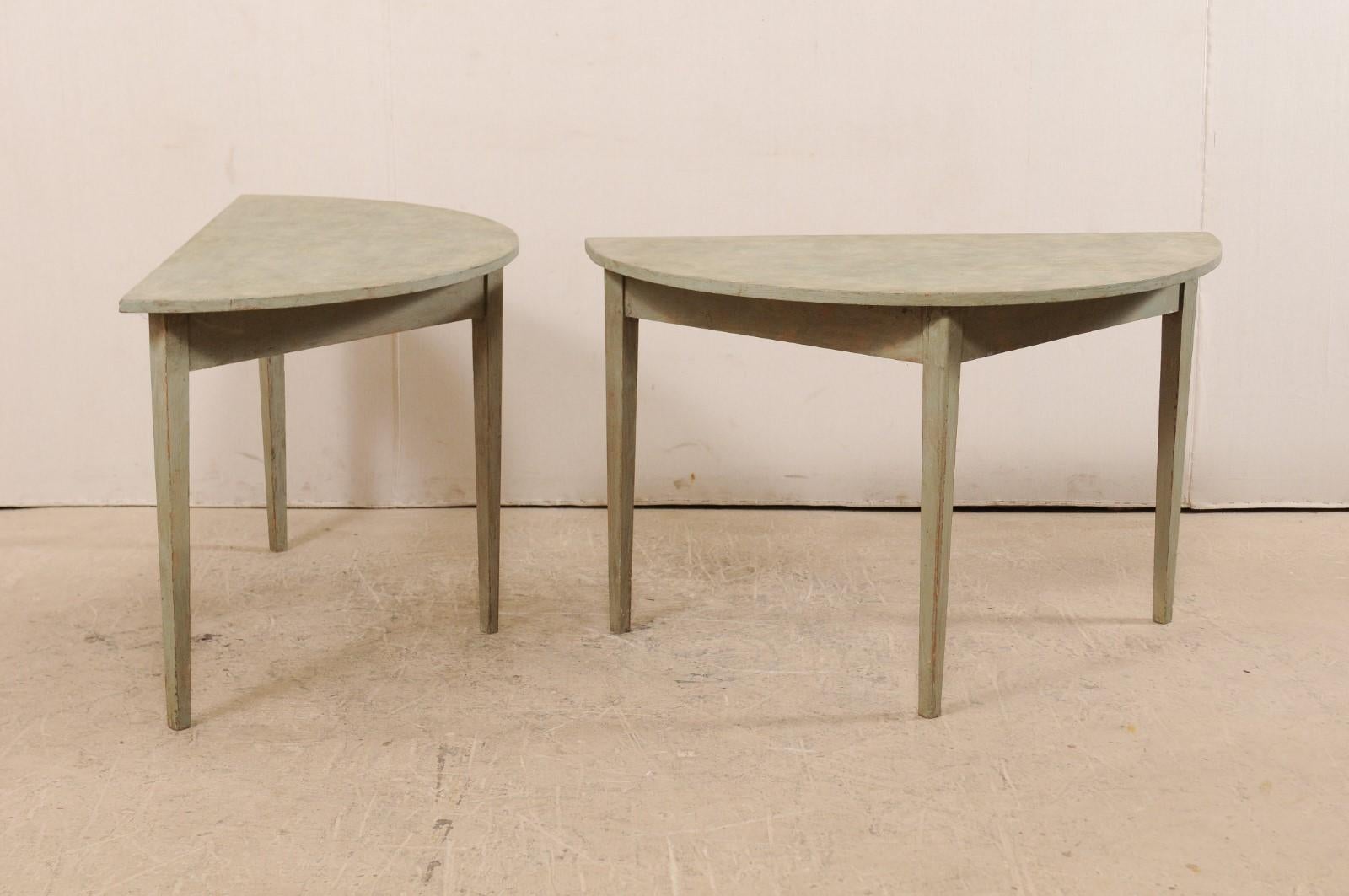 A pair of 19th century Swedish painted wood demilune tables. This pair of Swedish demilune tables from the 1880s features a semi-circular top over a triangular shaped, plain apron. These demilune tables are each raised upon three squared and gently