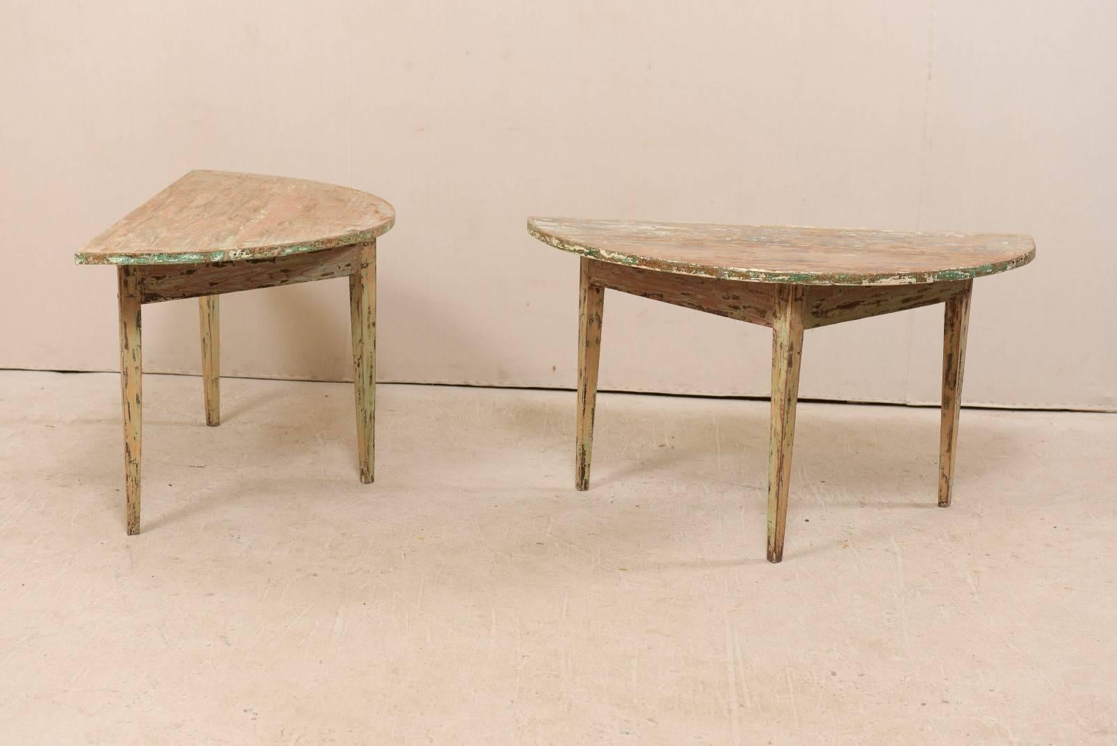 A pair of 19th century Swedish wooden demilune tables. This pair of Swedish demilune tables from the 1880s features a semi-circular top over a triangular shaped apron. These demilune tables are each raised upon three squared and gently tapered legs.