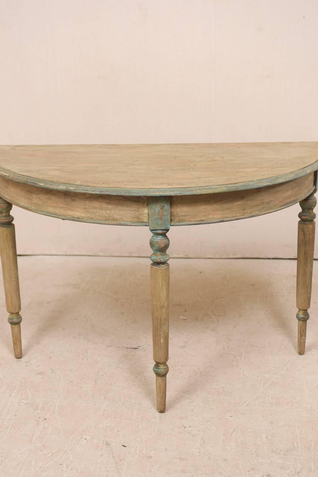 A pair of 19th century Swedish painted wood demilune tables. This pair of Swedish demi-lune table features a semi-circular top over a rounded shaped apron. These demi-lune tables are each raised upon three beautifully turned legs. The tables are
