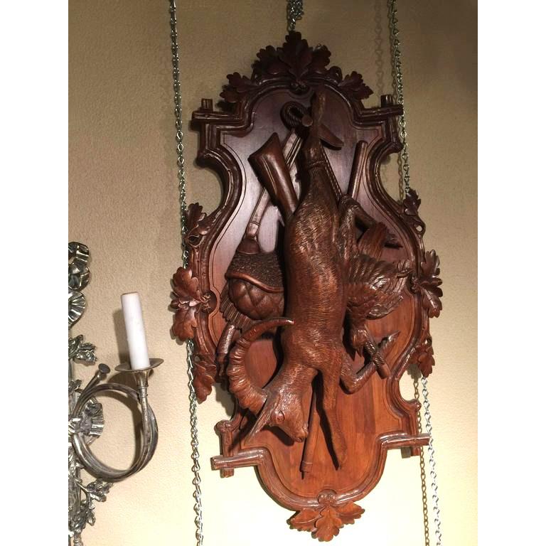 These elegant antique Black Forest carved wall plaques were crafted in Switzerland, circa 1880. Each fruitwood trophy features a large deer or ibex, along with pheasant, rifle and satchel decor; each plaque carved in high relief is further