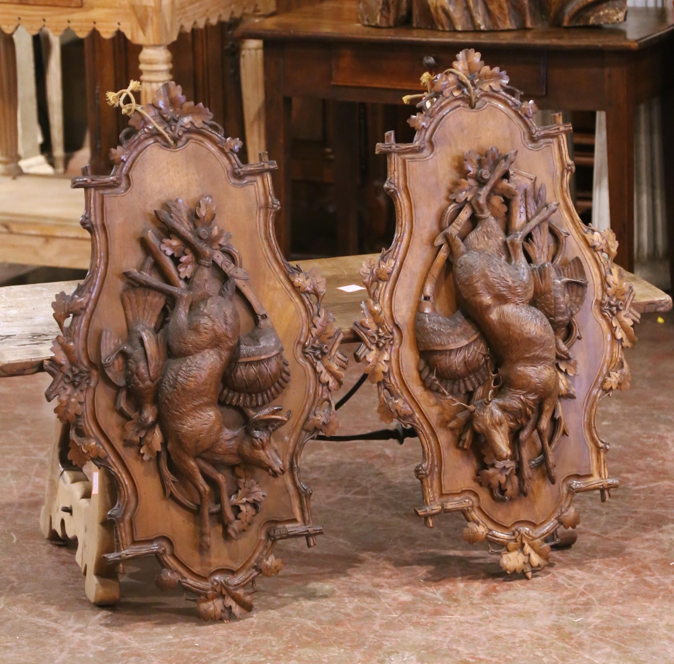Cette remarquable paire de trophées muraux a été sculptée à la main dans la région de la Forêt-Noire, en Suisse, vers 1870. Exécutée en noyer richement grainé et haute de près d'un mètre, chaque plaque est un tour de force de la sculpture