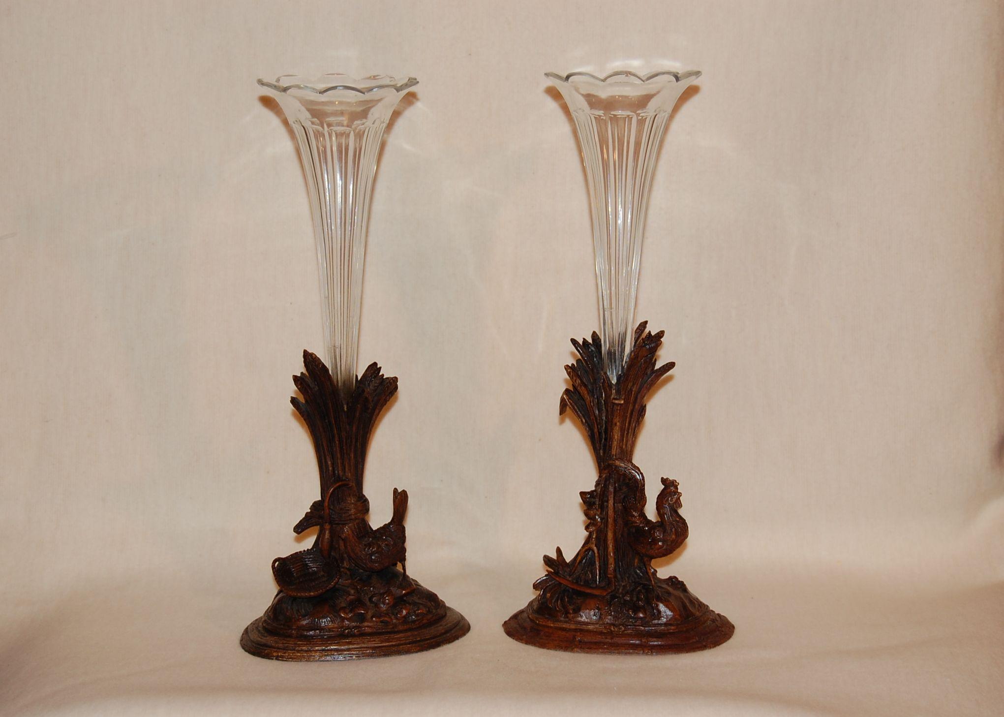 A beautiful pair of antique carved walnut vases (epergnes) crafted in Switzerland, circa 1870. Each vase features intricate hand carved roosters, a wicker basket, a pitchfork and sickle. Resting on a base of leaves and grasses. The upper sections